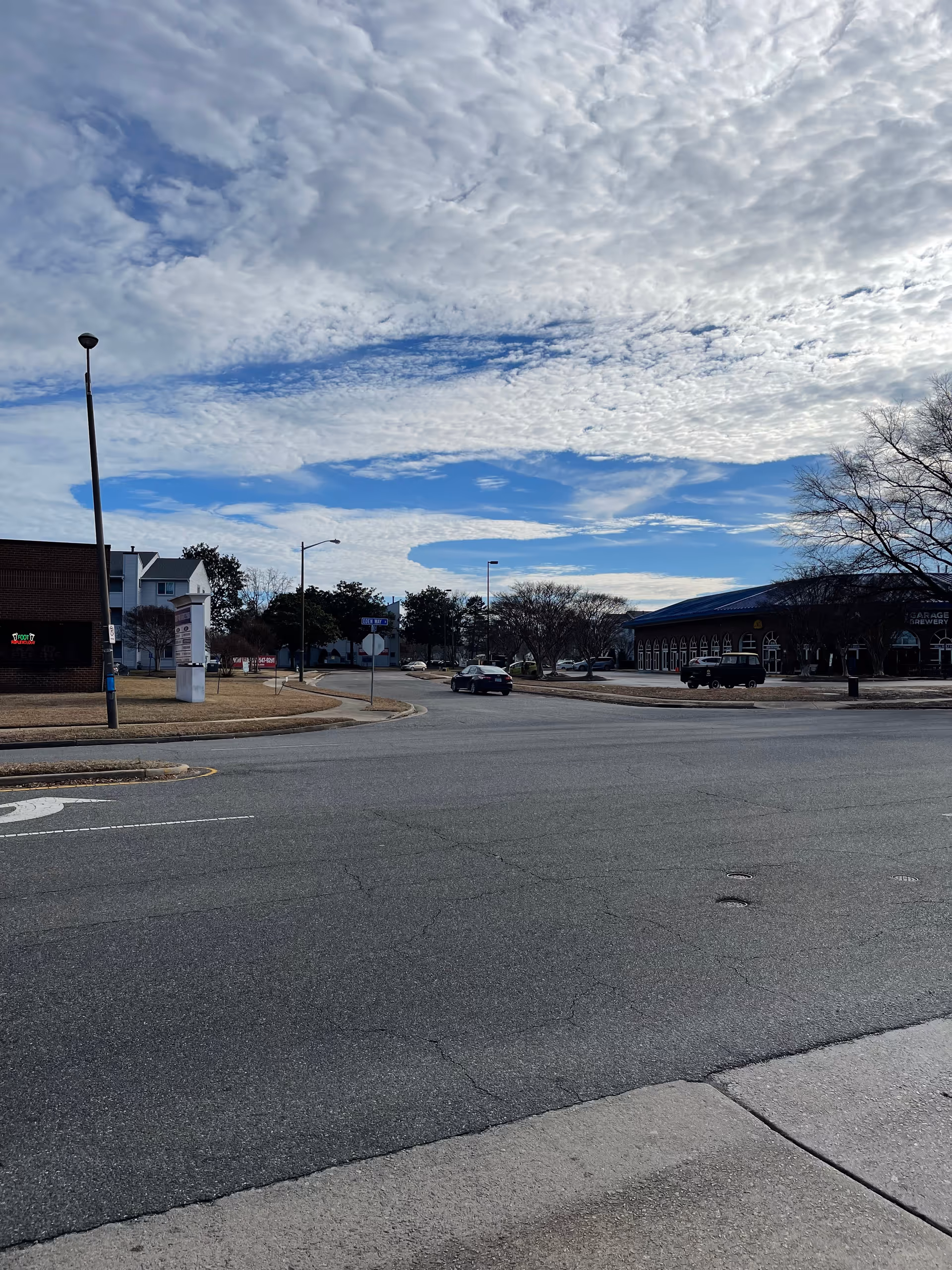 Wide street intersection outside a senior facility with storefronts and cloudy sky.