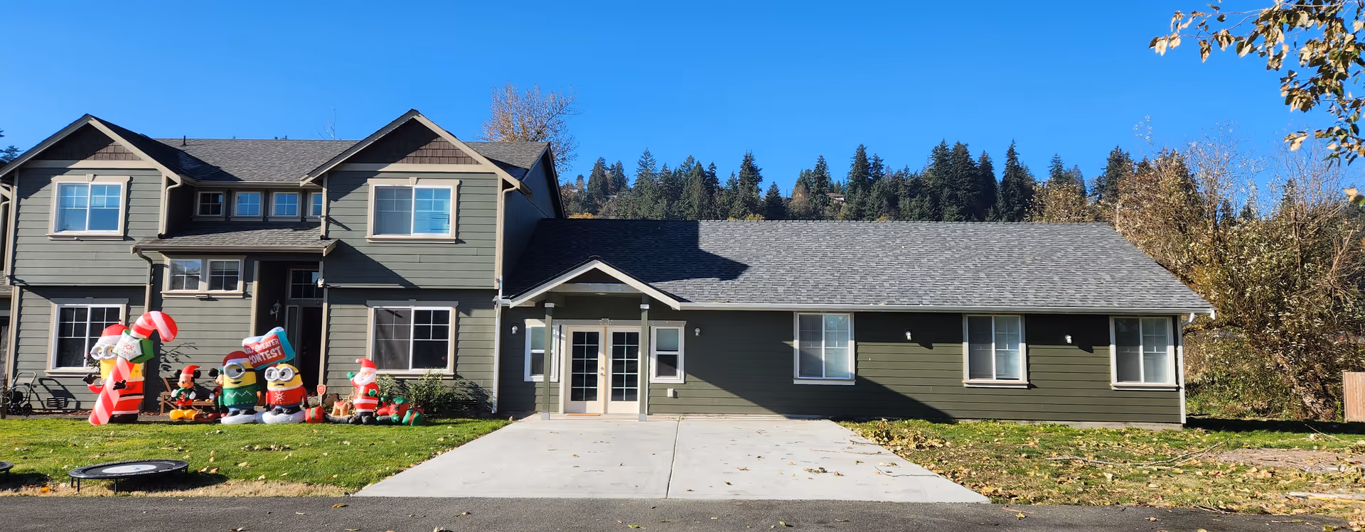 Exterior view of a green Pacific Adult Family Home LLC with central entrance and inflatables.