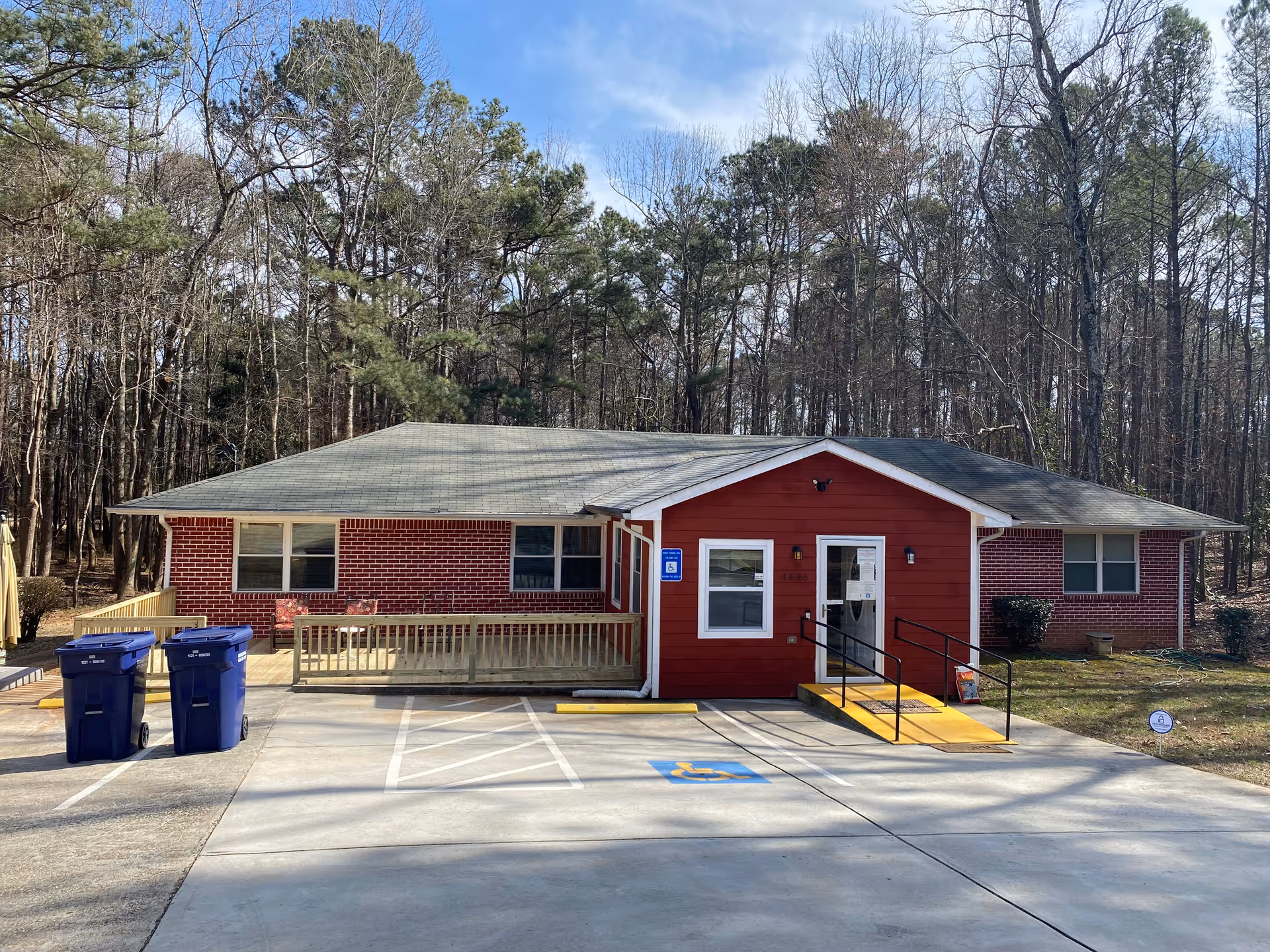Front view of a red brick care home with entrance ramp and handicap parking.