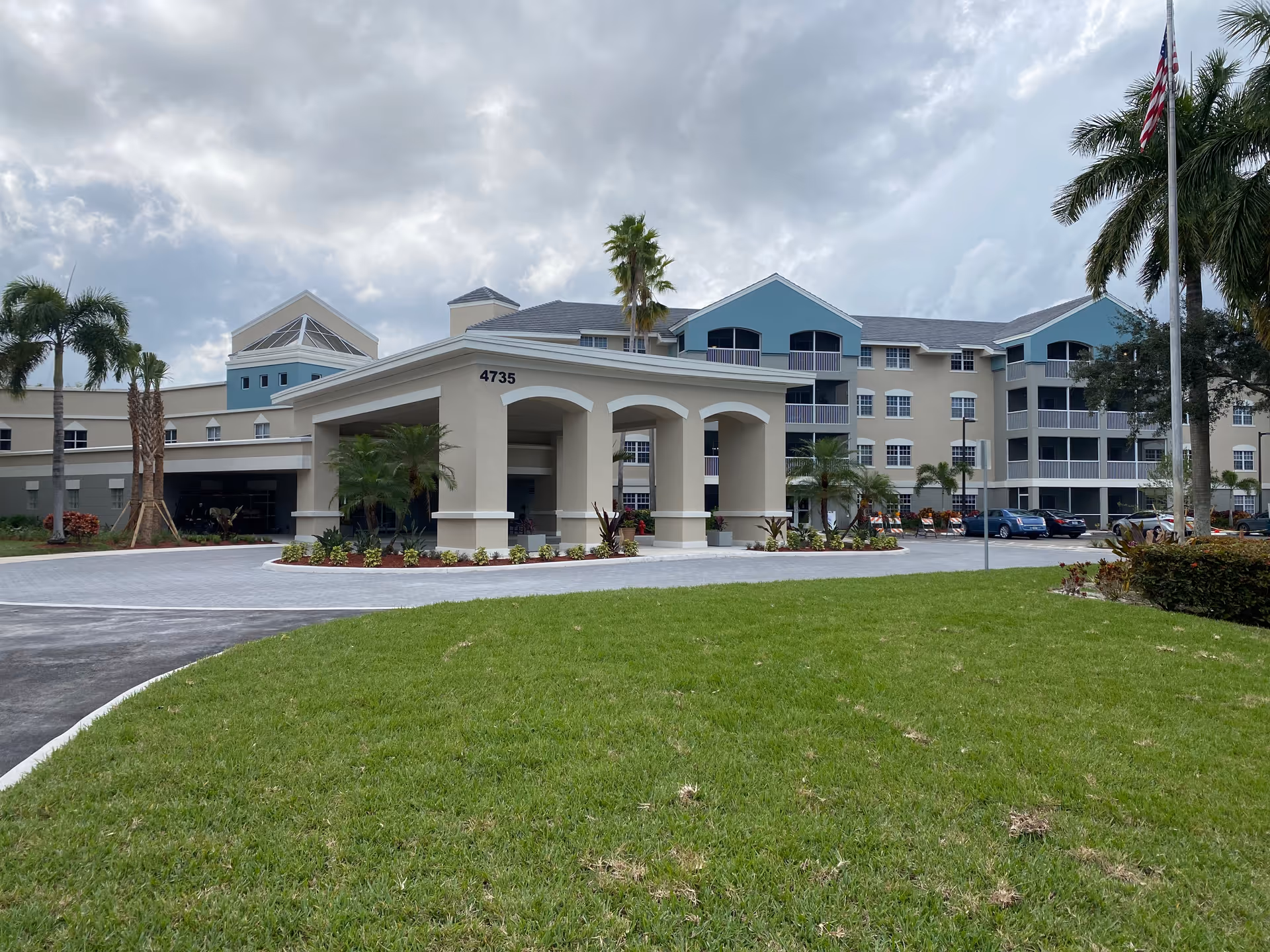 Exterior view of Discovery Village at Boynton Beach with porte-cochere entrance and palm trees.