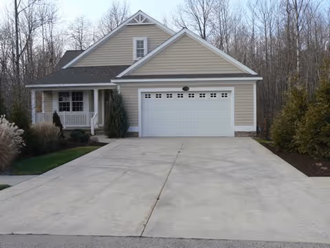 Front view of a beige house with a two-car garage and long driveway