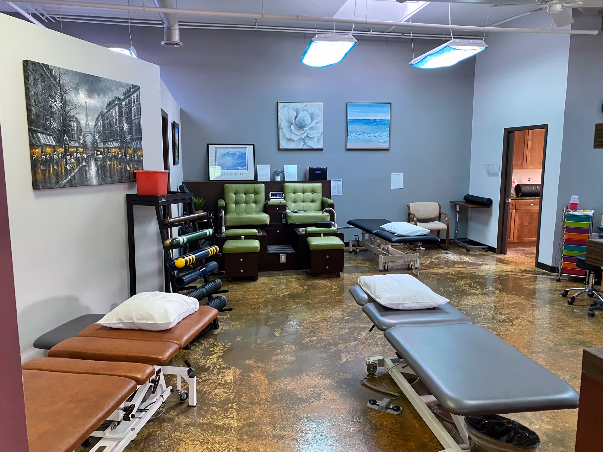 Indoor therapy area with treatment tables, weights, and seating in a rehab clinic.
