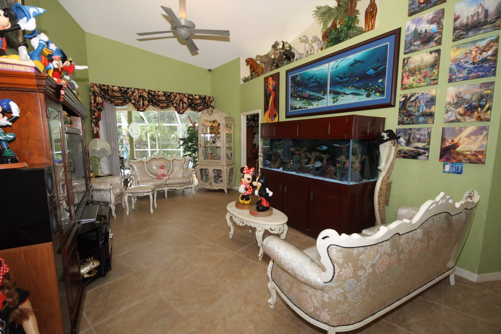 Bright, ornate living room with a fish tank, white furniture, and wall photo collage.