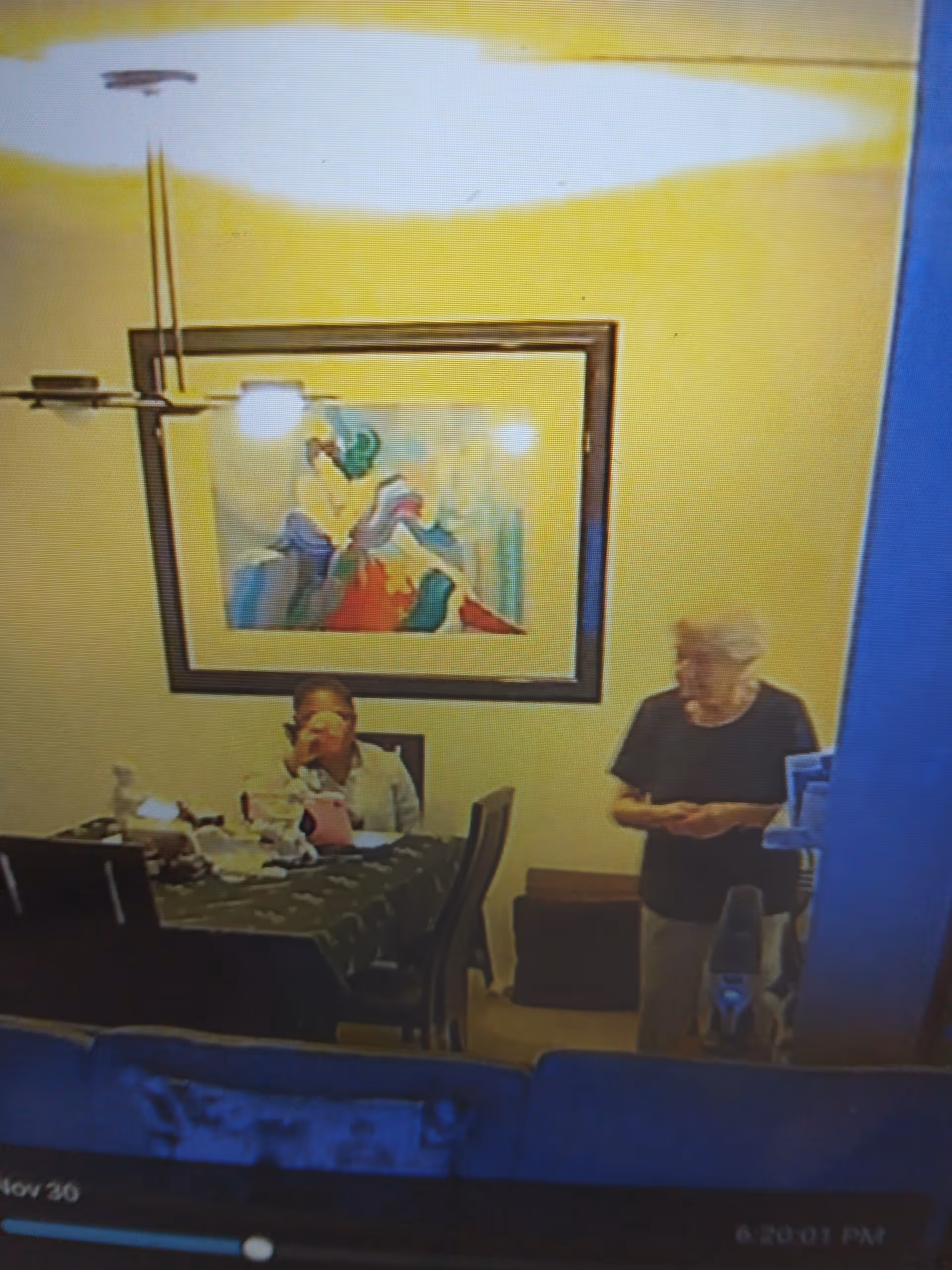 Two people sit at a table in a yellow-walled dining room.