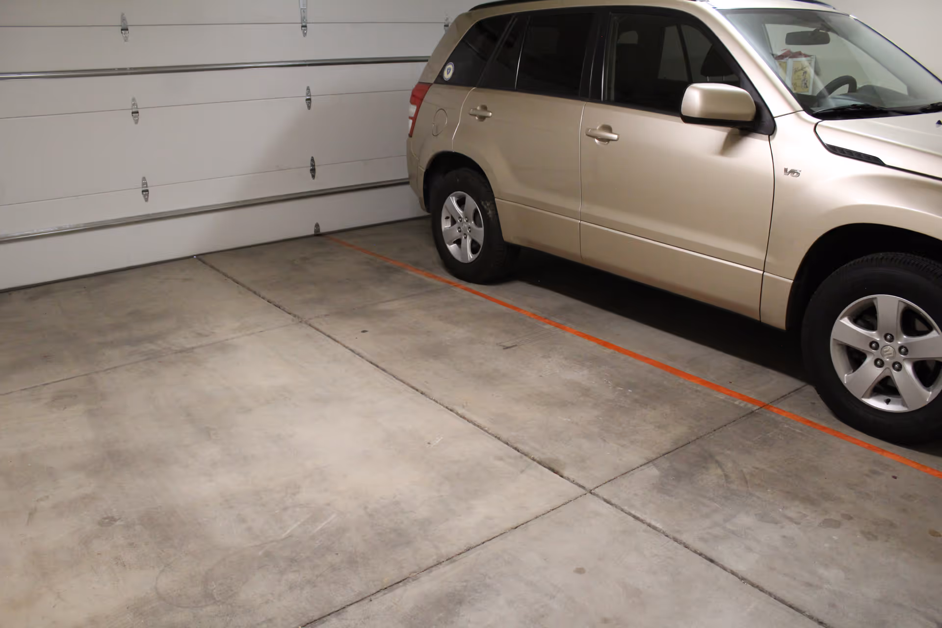 Beige SUV parked inside a residential garage with concrete floor and closed door.