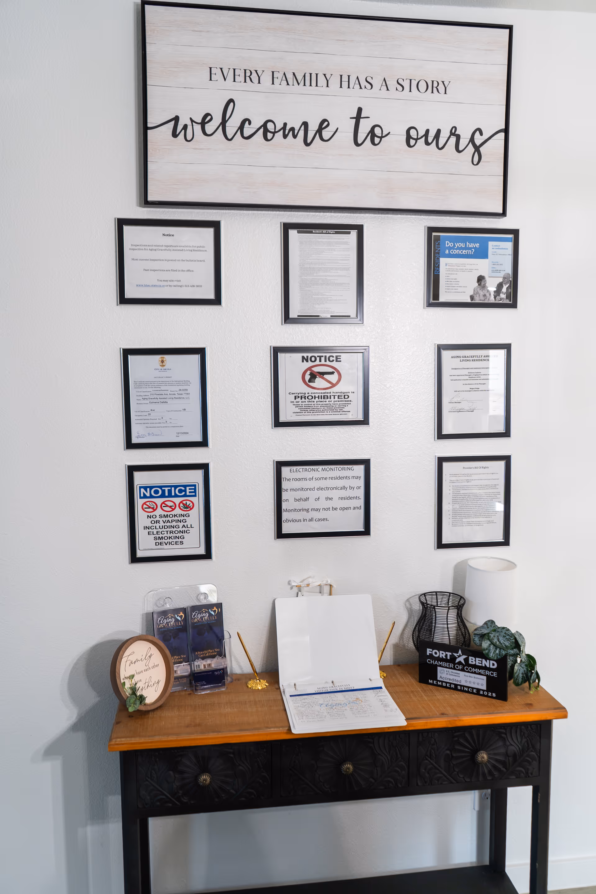 Reception area with framed notices on the wall and a wooden console table.