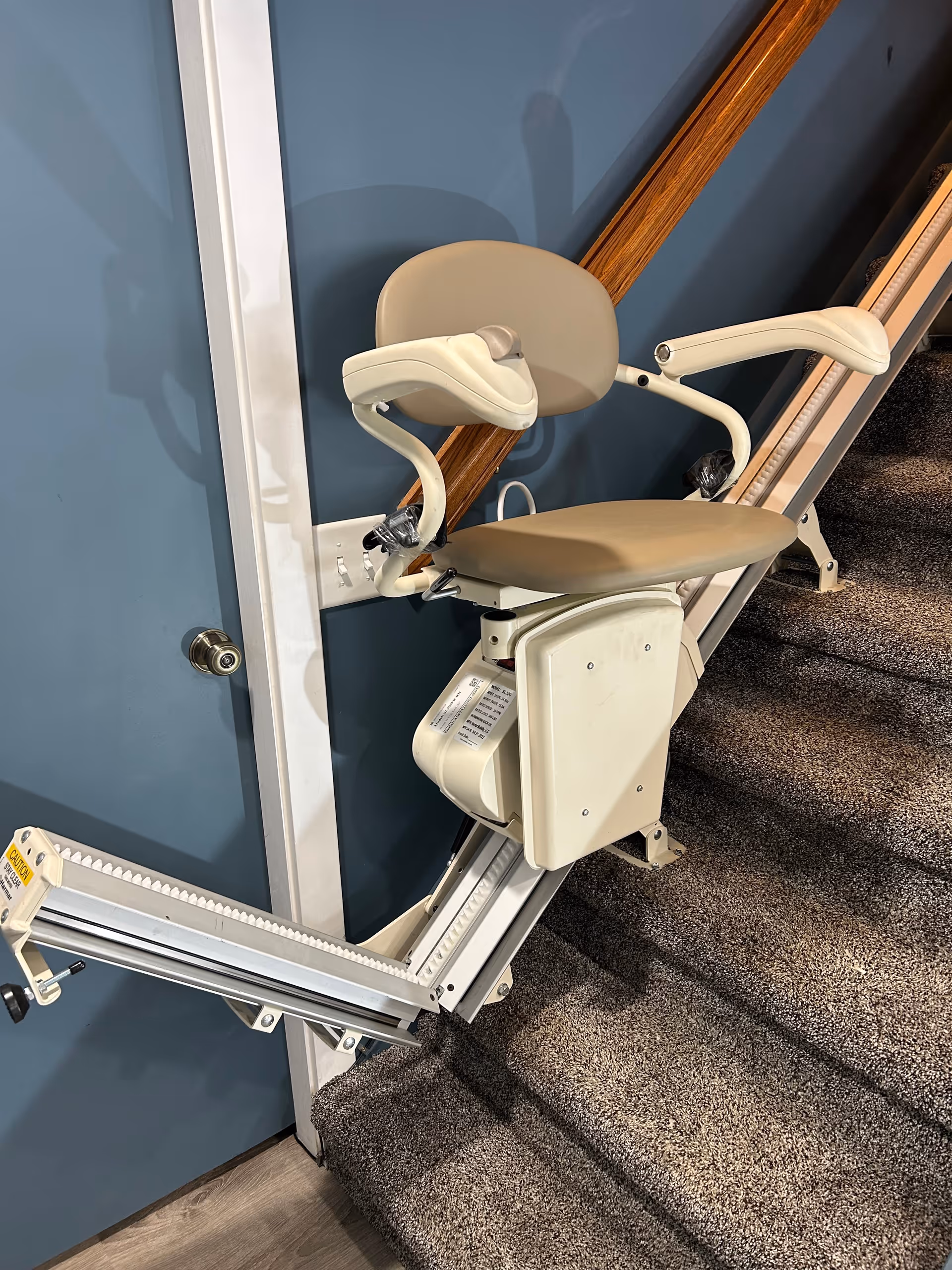 Beige stairlift chair attached to a blue interior staircase.