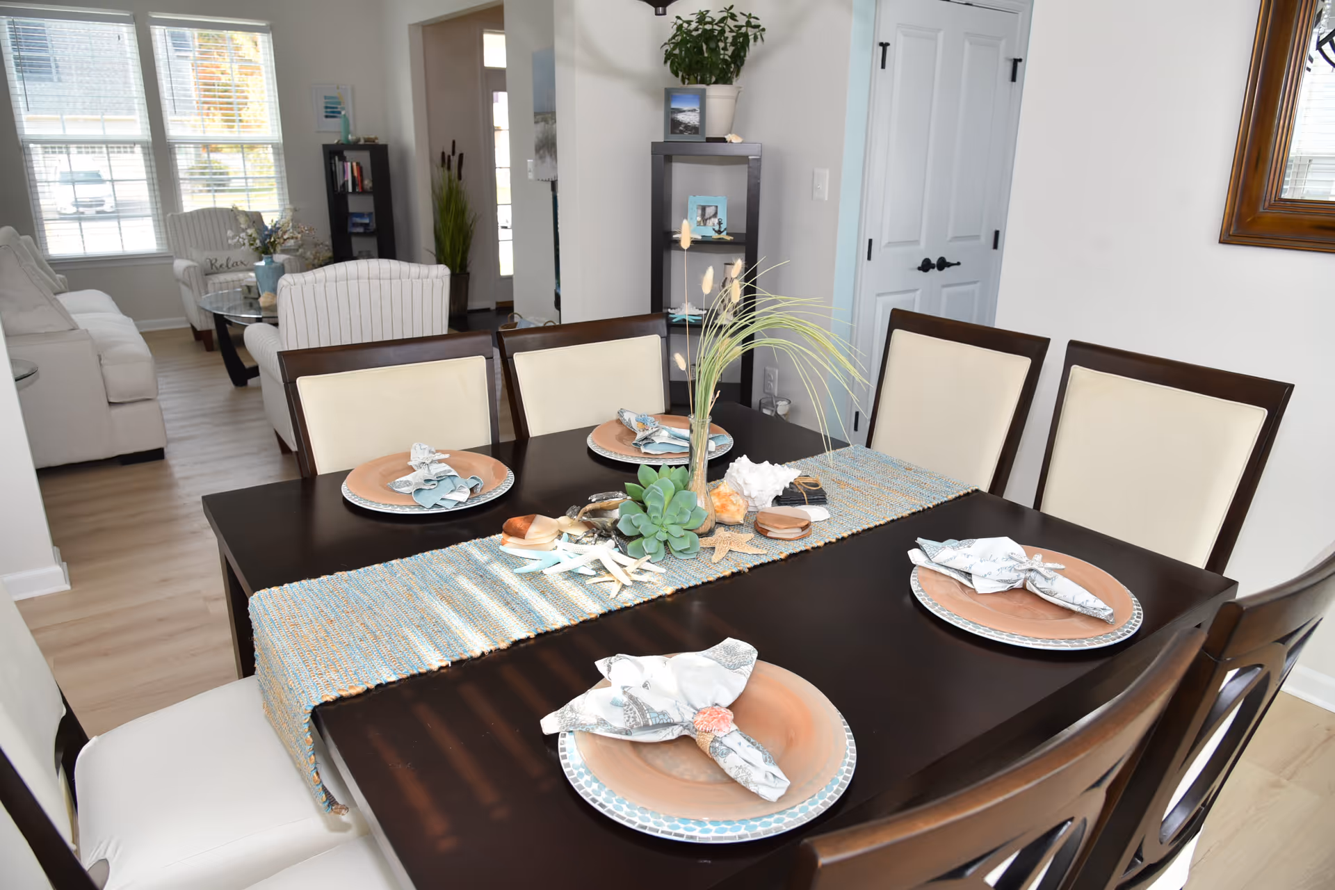 Dark dining table with place settings and a decorative centerpiece in a bright dining area.