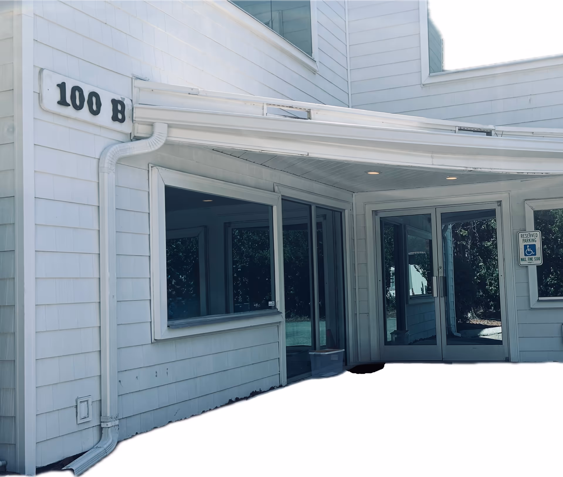 White exterior of a senior facility with glass front doors, curved canopy, and 100 B sign.
