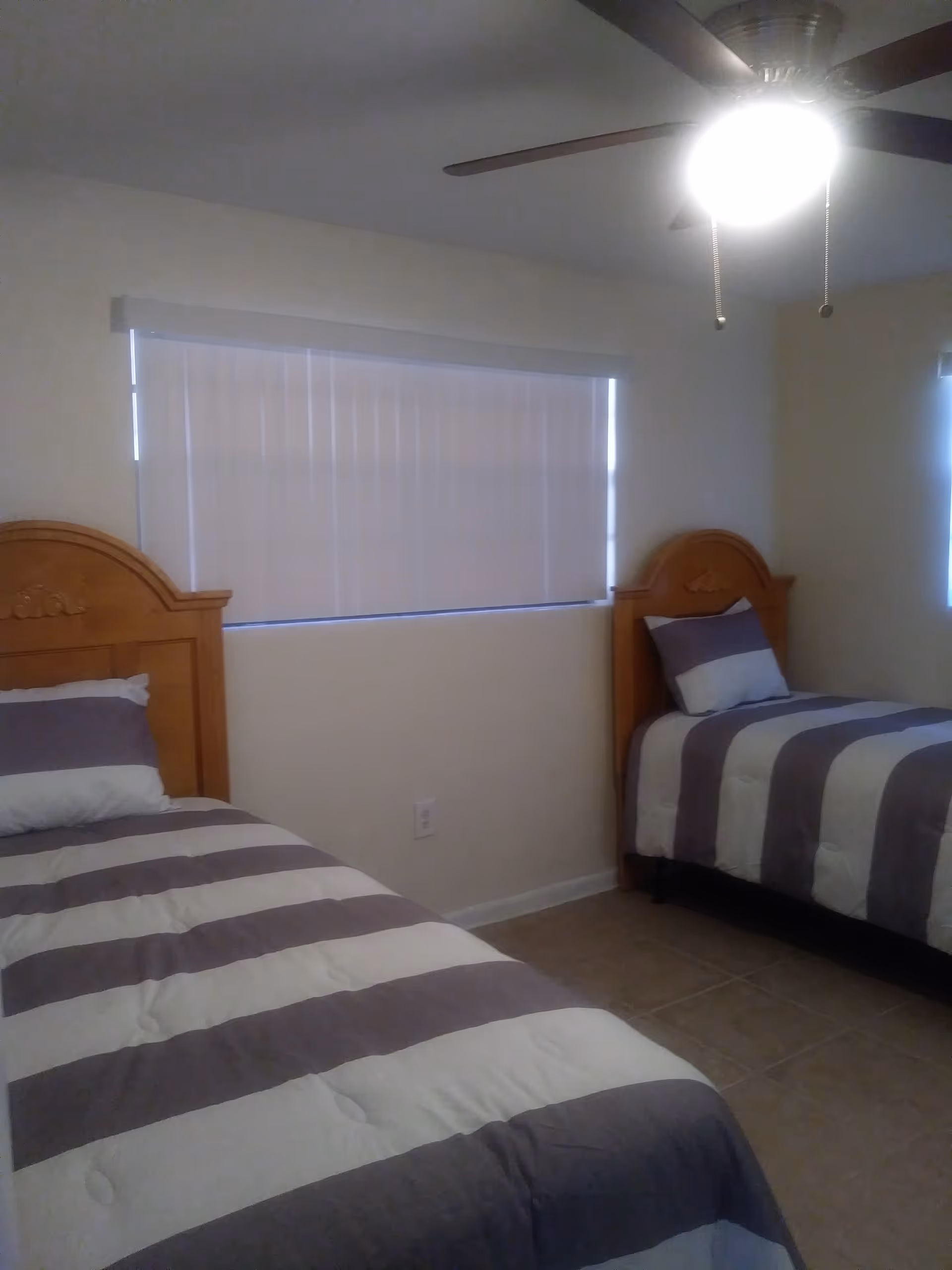 Two twin beds with striped comforters sit in a clean, well-lit bedroom.