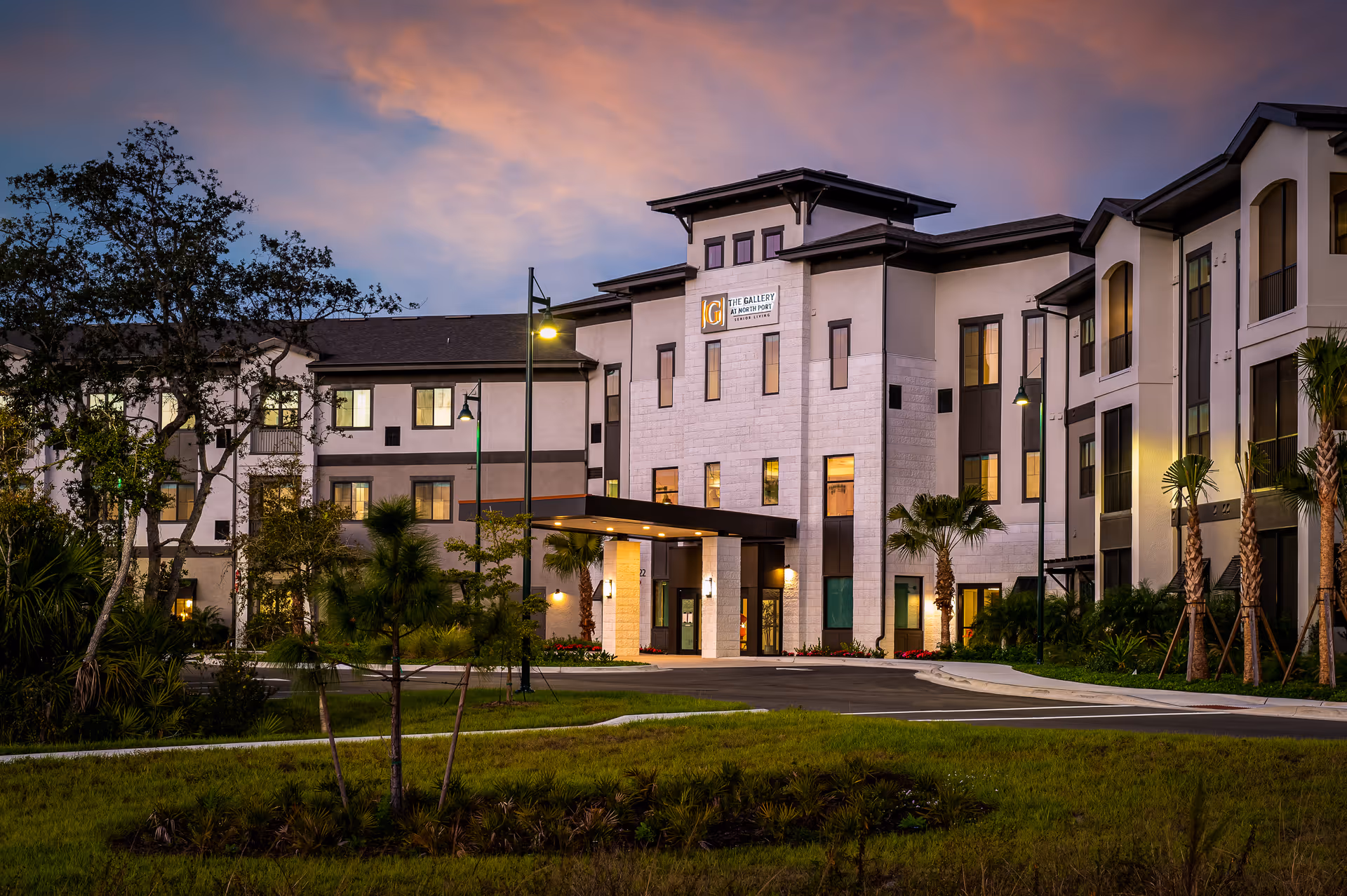 Exterior view of The Gallery at North Port, a modern senior living building with landscaping.