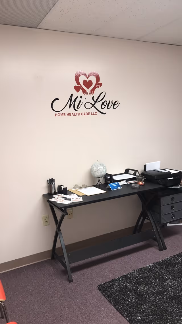 The Mi' Love Home Health Care logo appears on a wall beside a desk and printer.