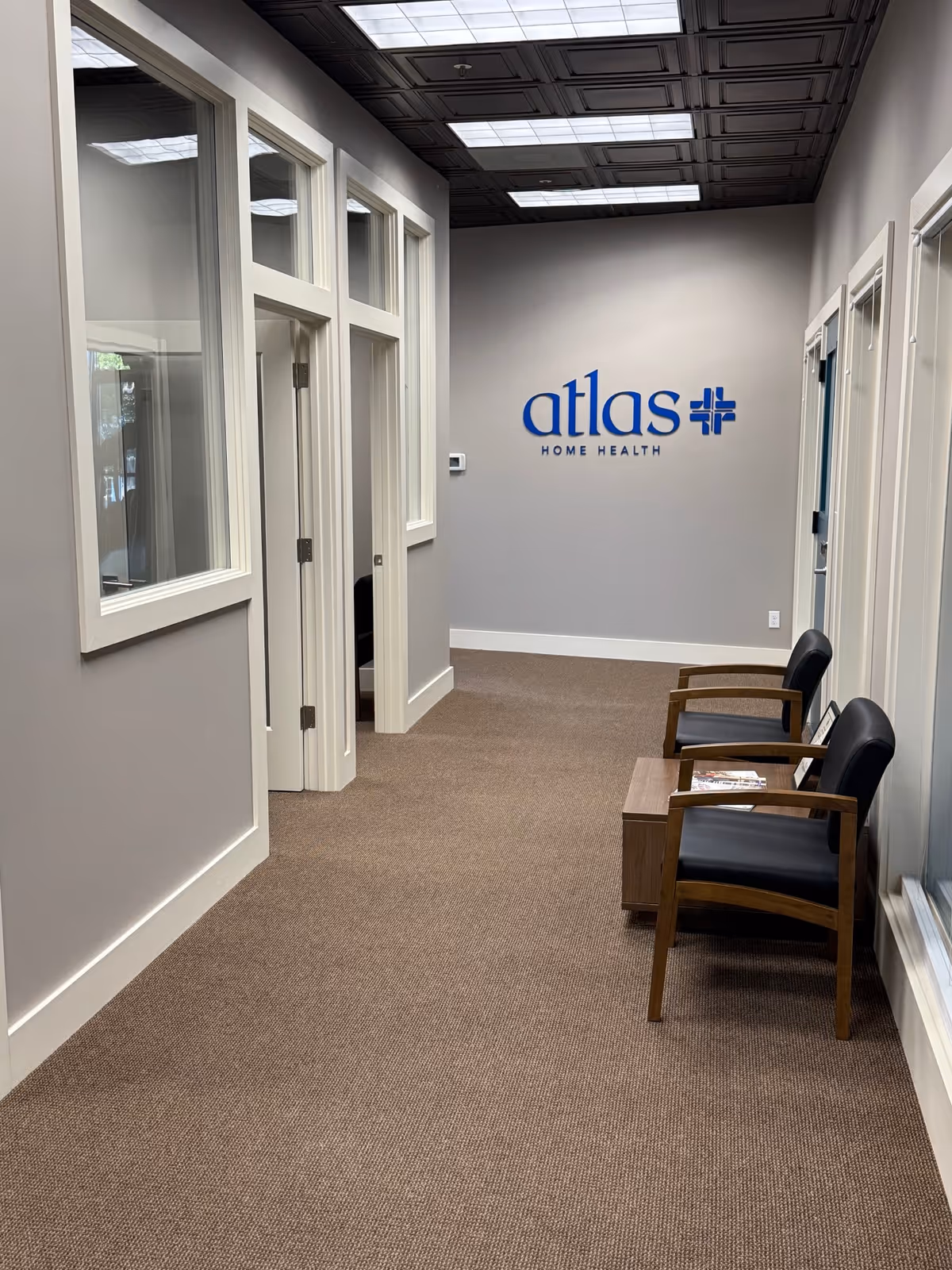 Interior corridor at Atlas Home Health with waiting chairs and a wall logo.