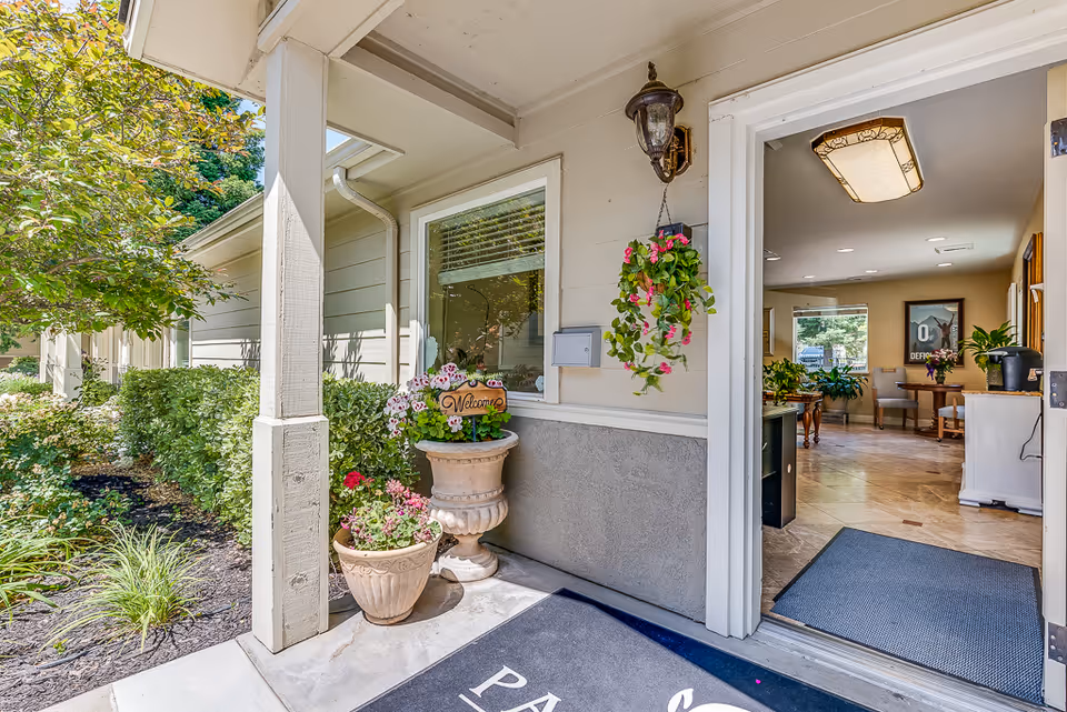 Entrance to a memory care facility with potted plants and welcoming decor.