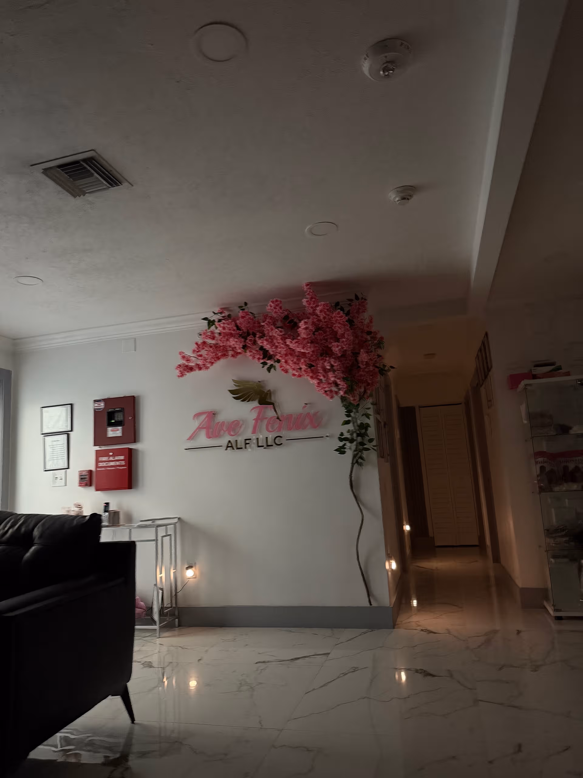 Indoor lobby of Ave Fenix ALF LLC featuring pink floral arrangement and sign