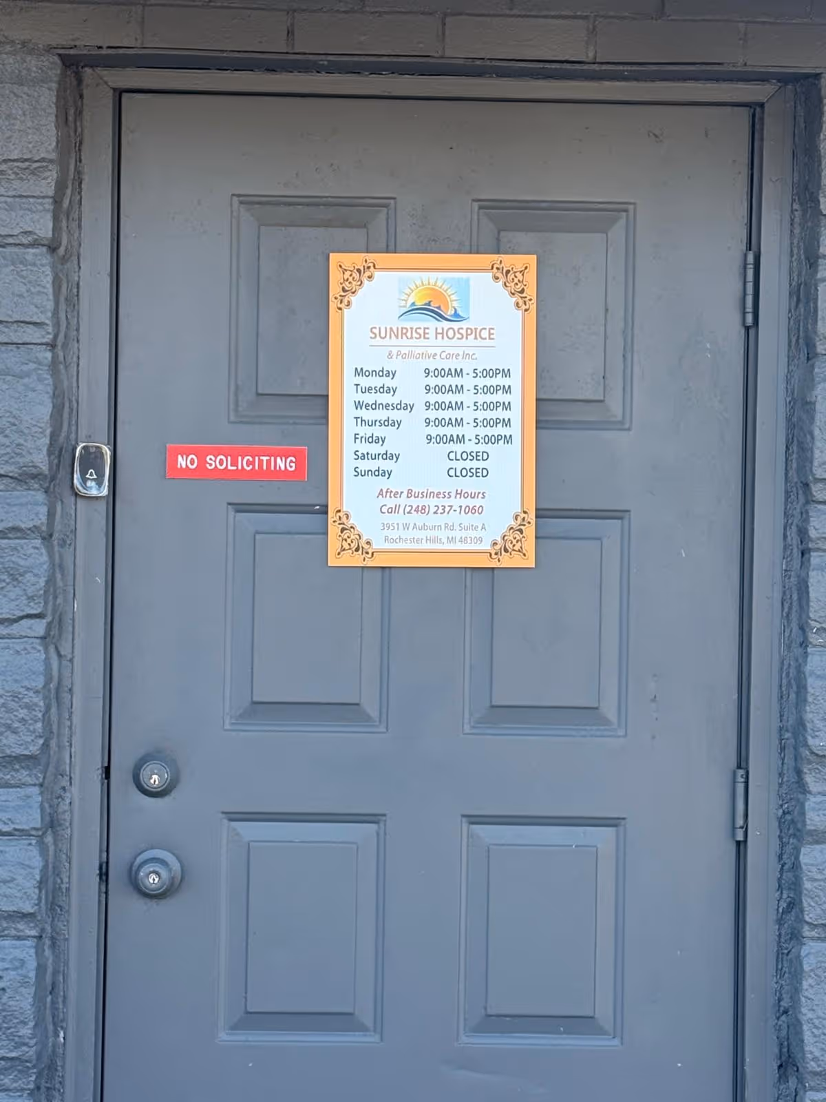 Gray exterior door with Sunrise Hospice sign and a red No Soliciting plaque