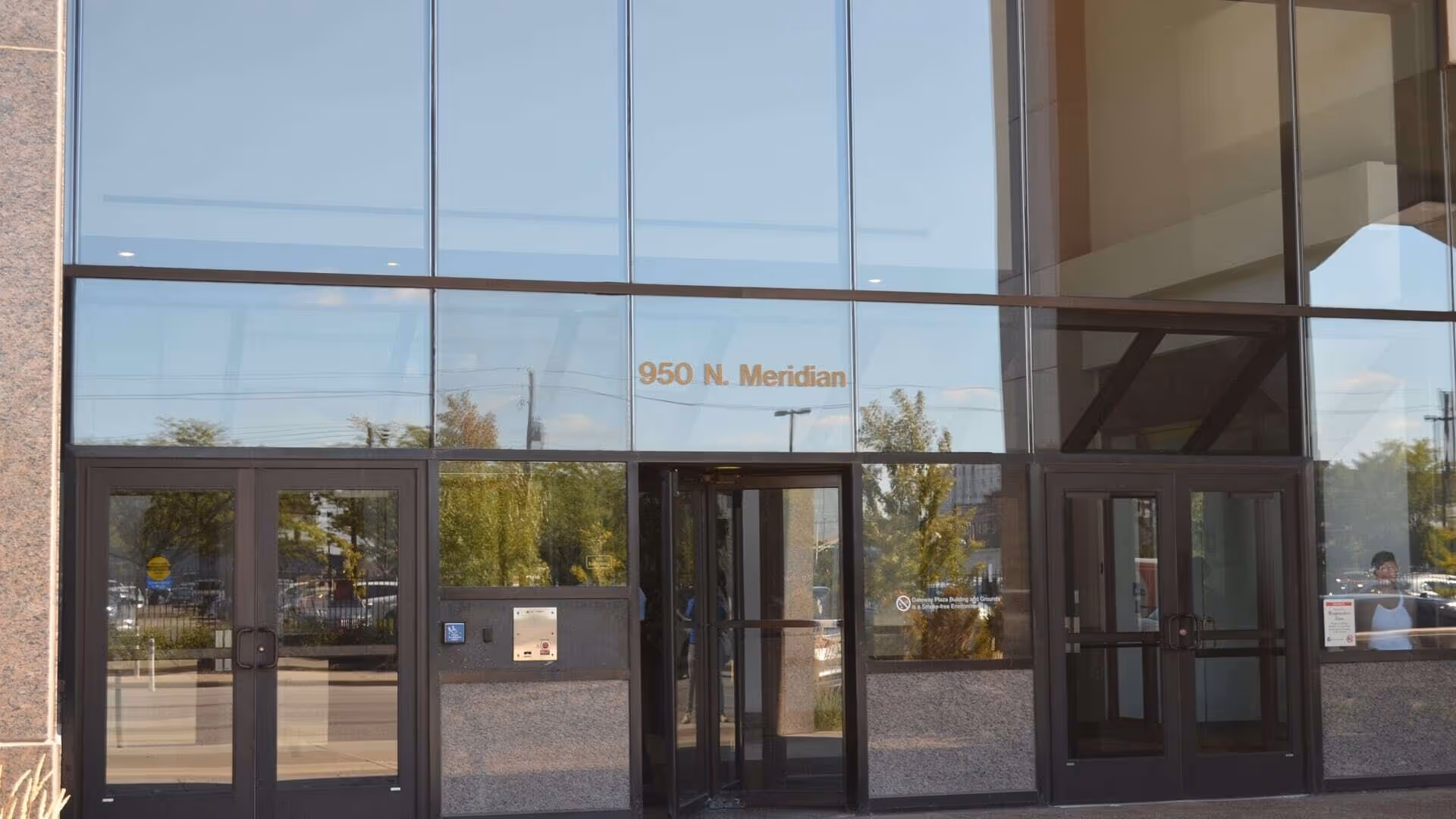 Glass-fronted building entrance with double doors and 950 N. Meridian plaque.
