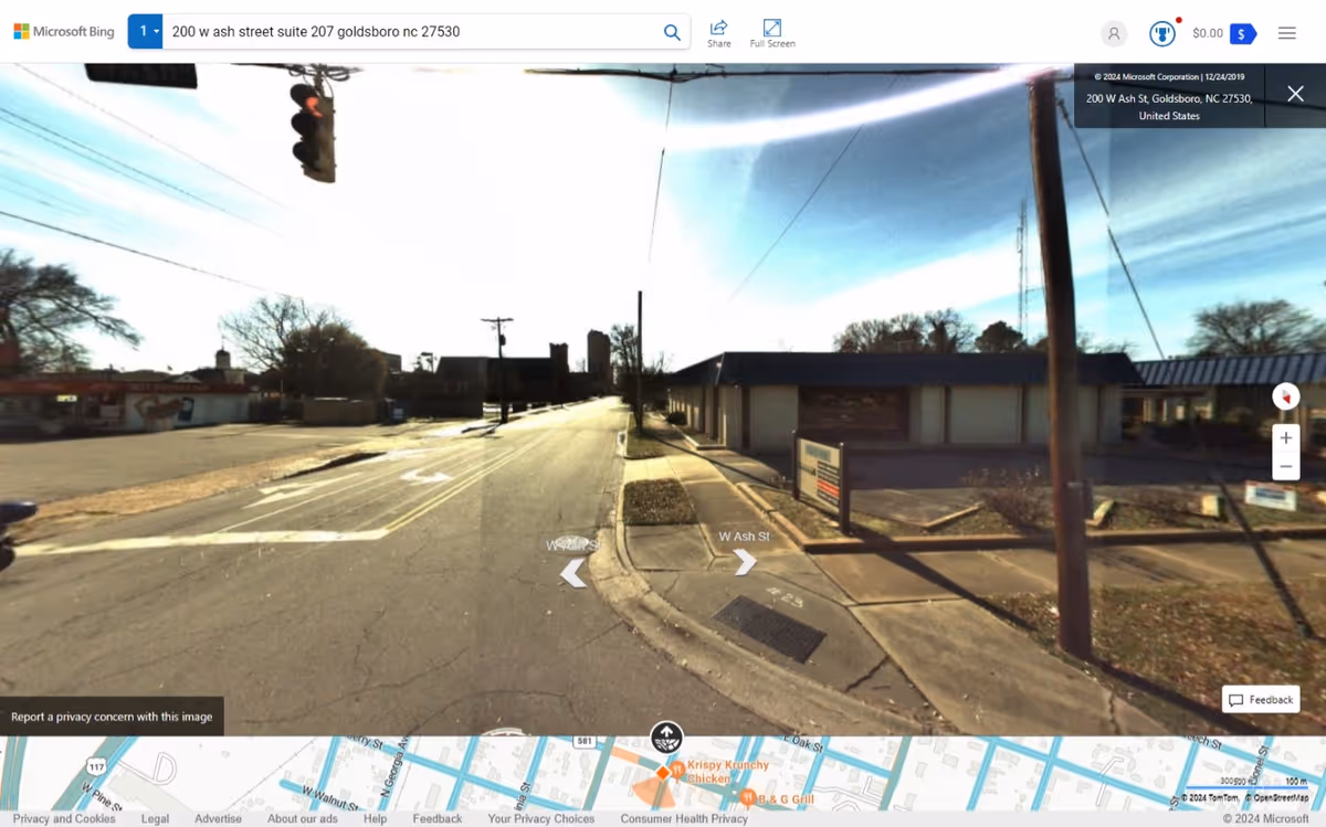 Exterior street view of a single-story building with a sidewalk and utility poles.