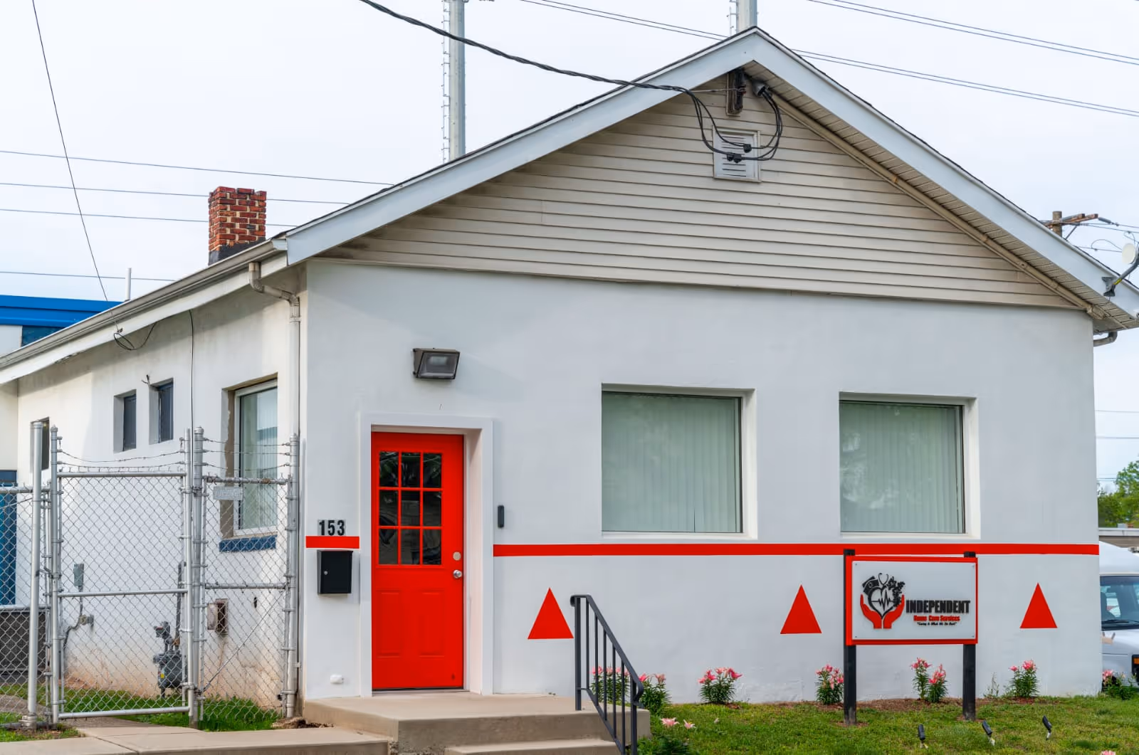 A small white building with a red door and trim, displaying an Independent sign.