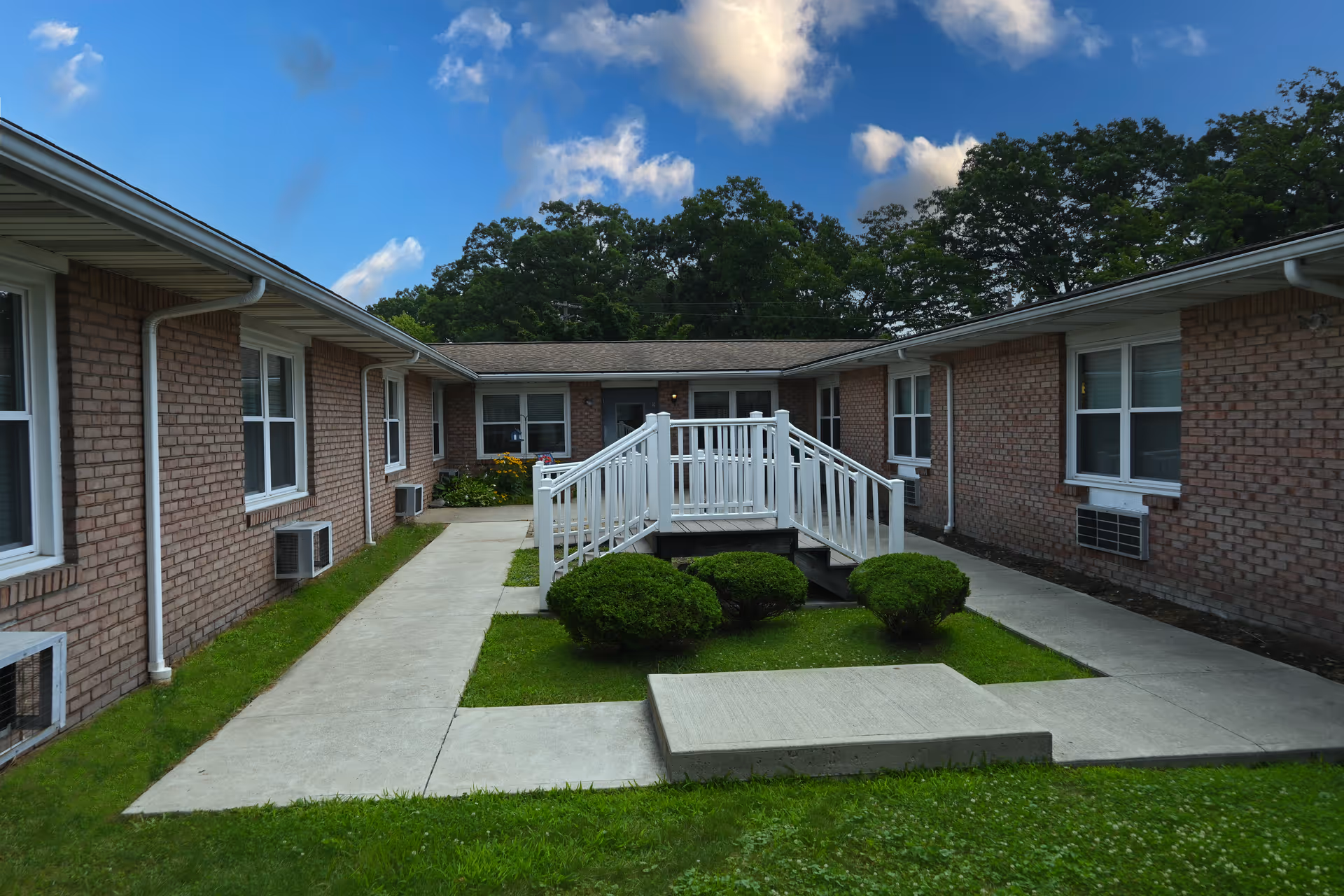 Brick senior living campus shows a central courtyard with a white ramp.