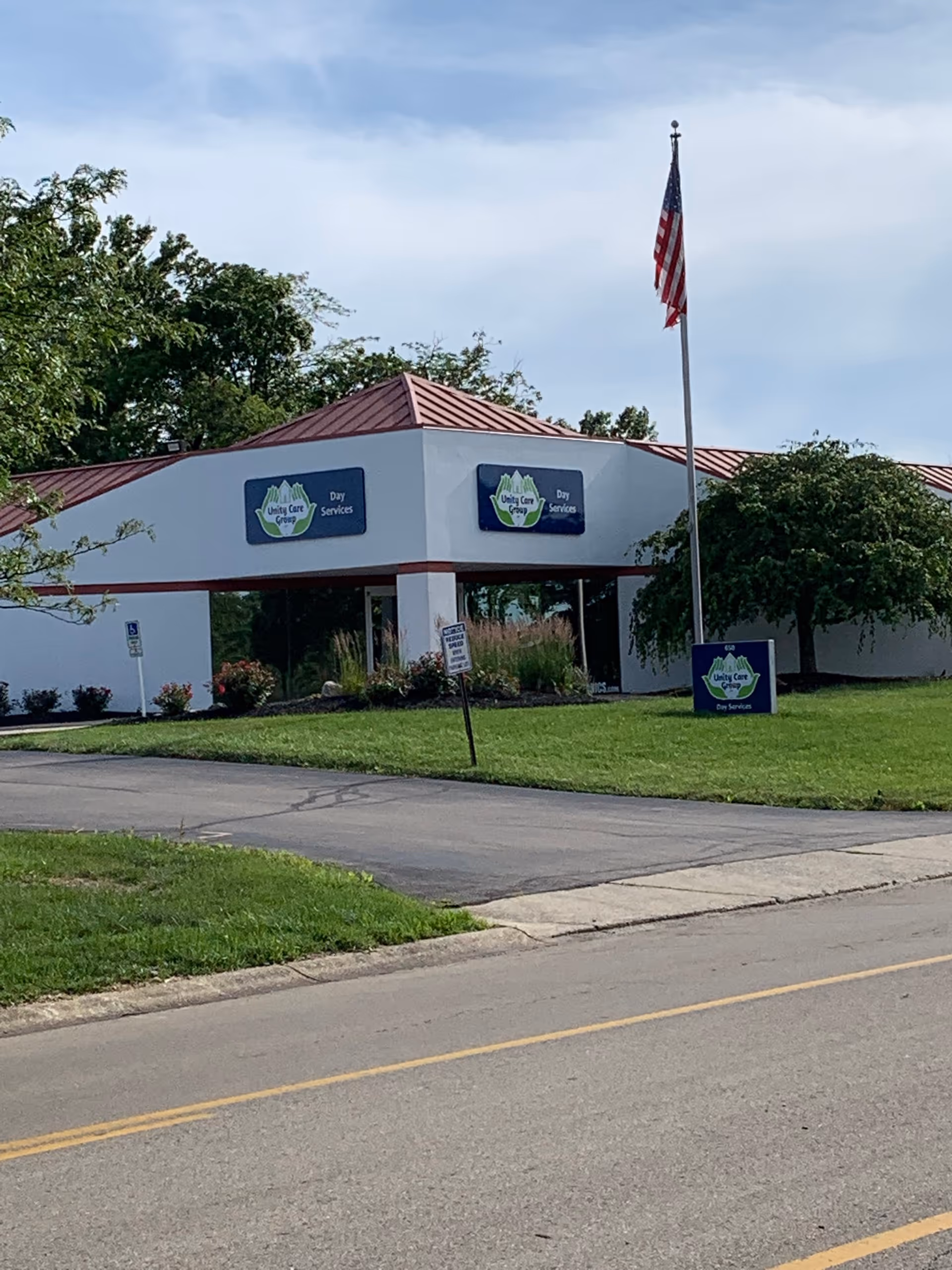White single-story senior facility exterior with Unity Care Group signs and an American flag.