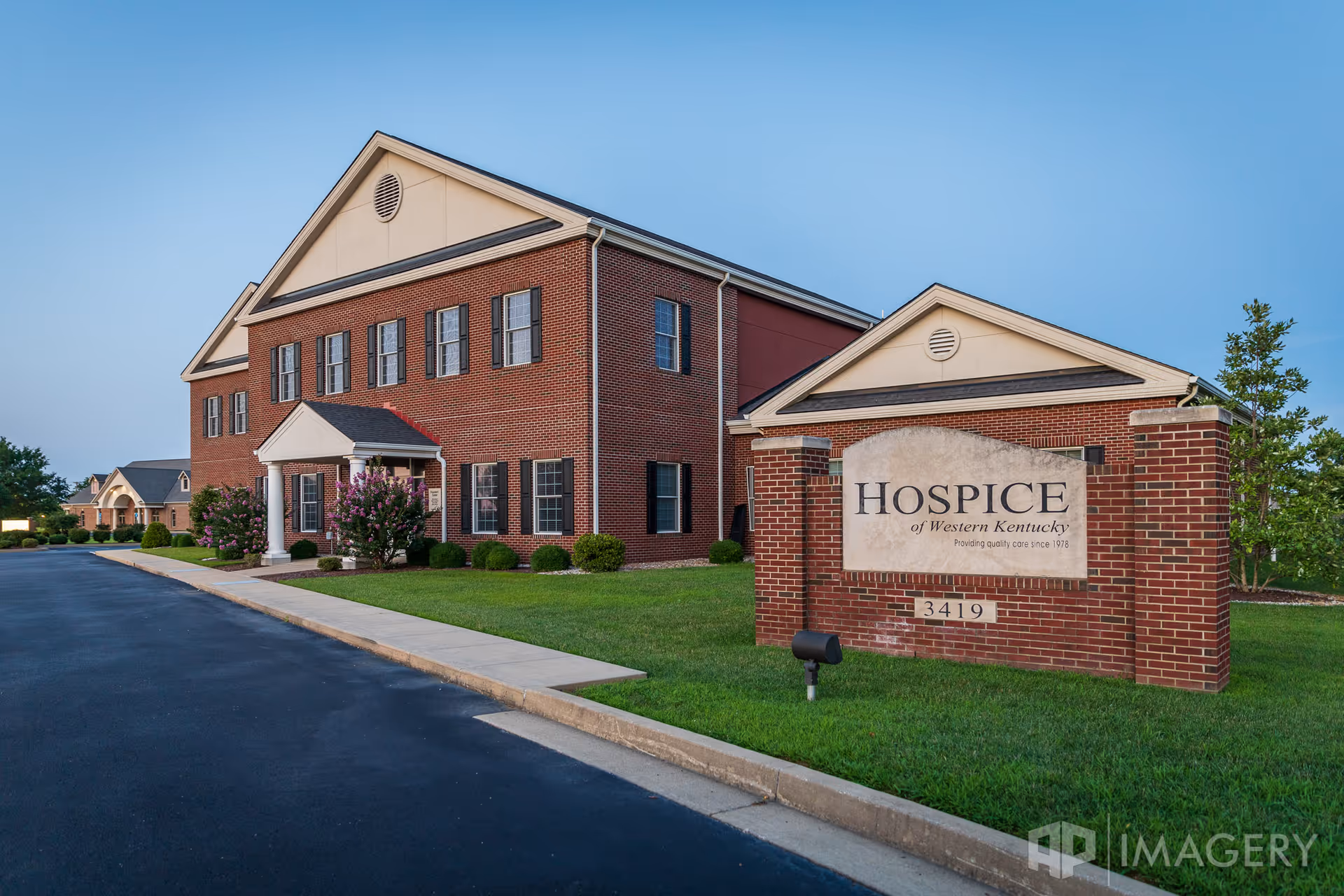 Brick hospice facility with a manicured lawn and a prominent sign reading Hospice of Western Kentucky.