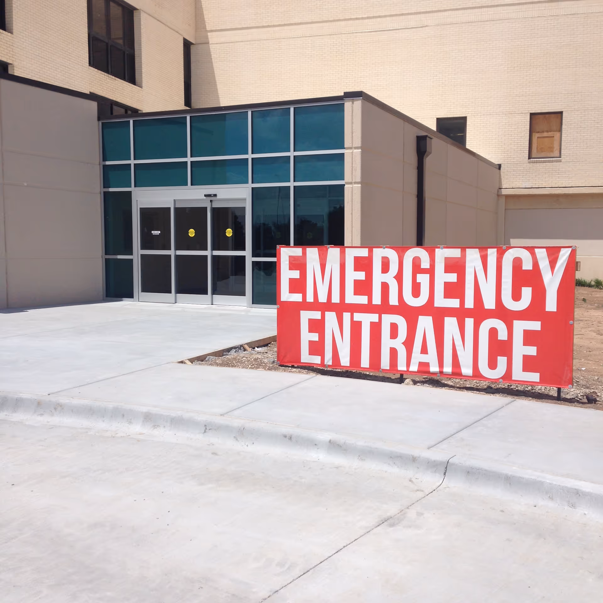 Exterior view of a hospital entrance with a large red Emergency Entrance sign.