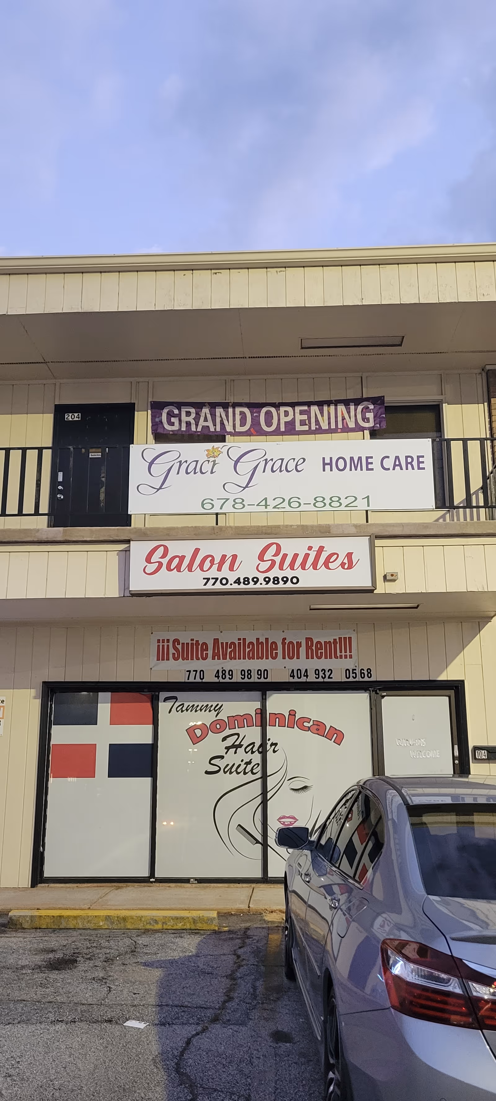 Exterior storefront with Grand Opening banners for Grace Grace Home Care and a parked car.