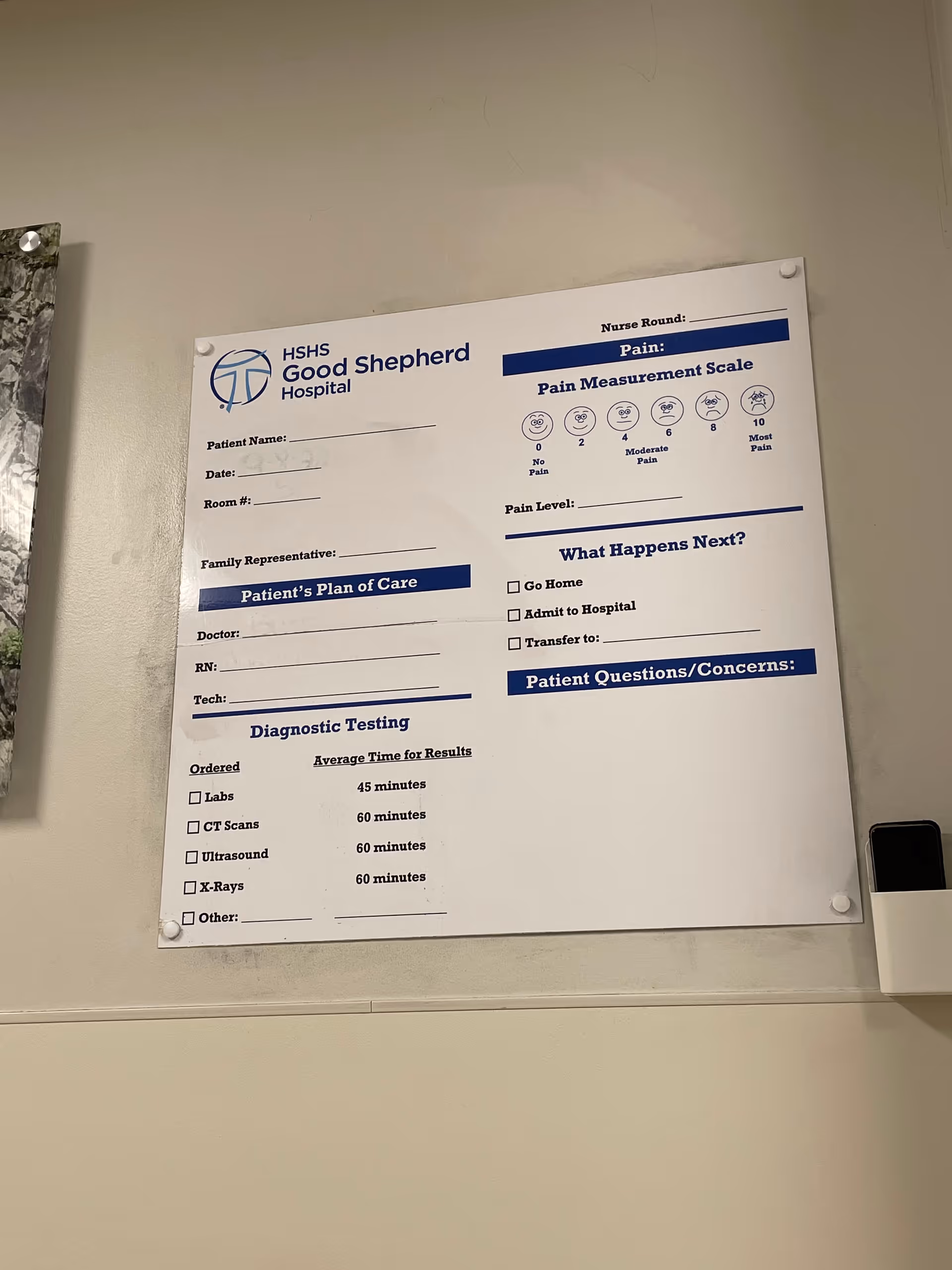 Large poster with Pain Measurement Scale and hospital branding mounted on wall.