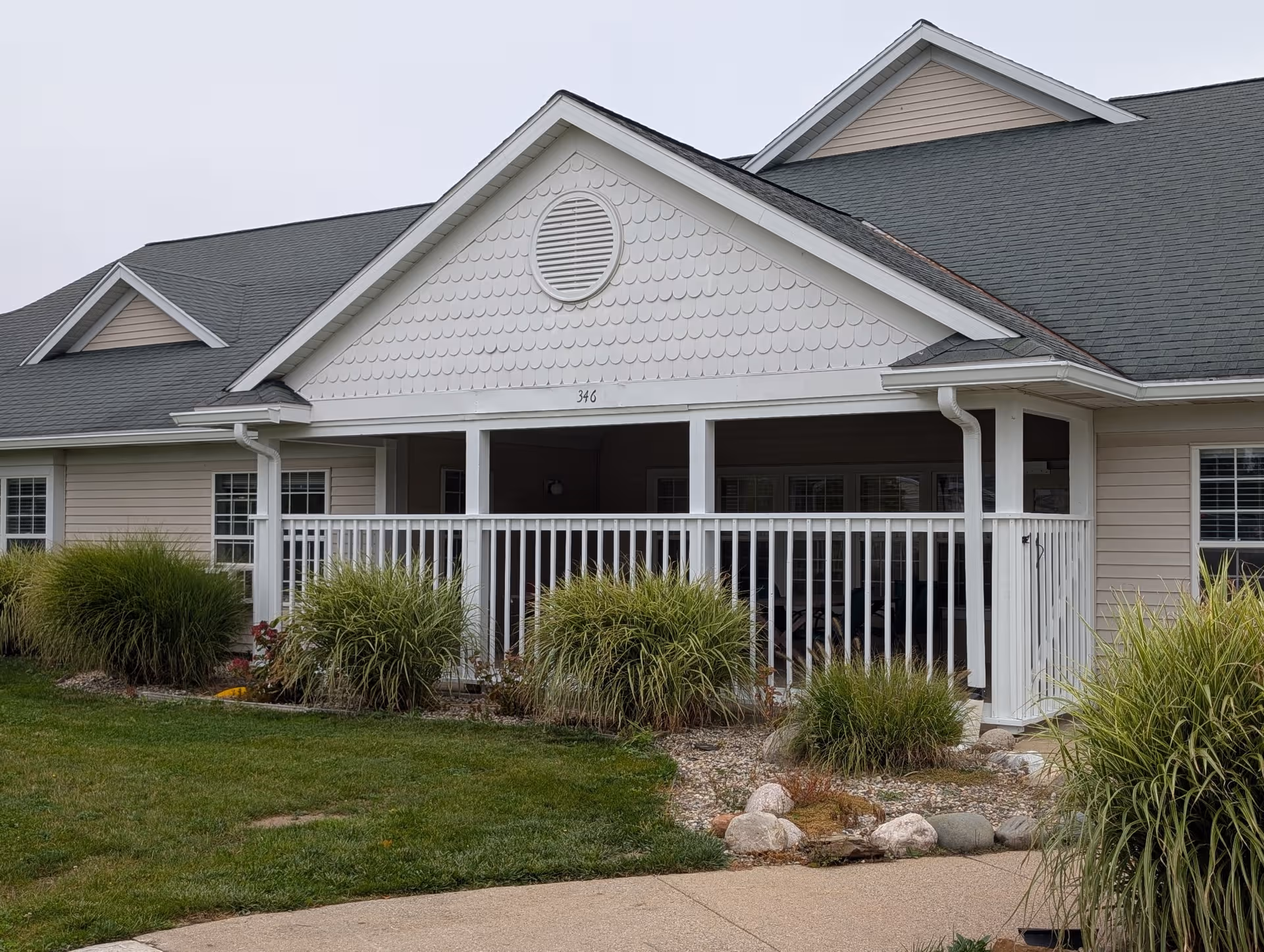 Single-story senior living facility with a covered front porch, white railing, and landscaped yard.
