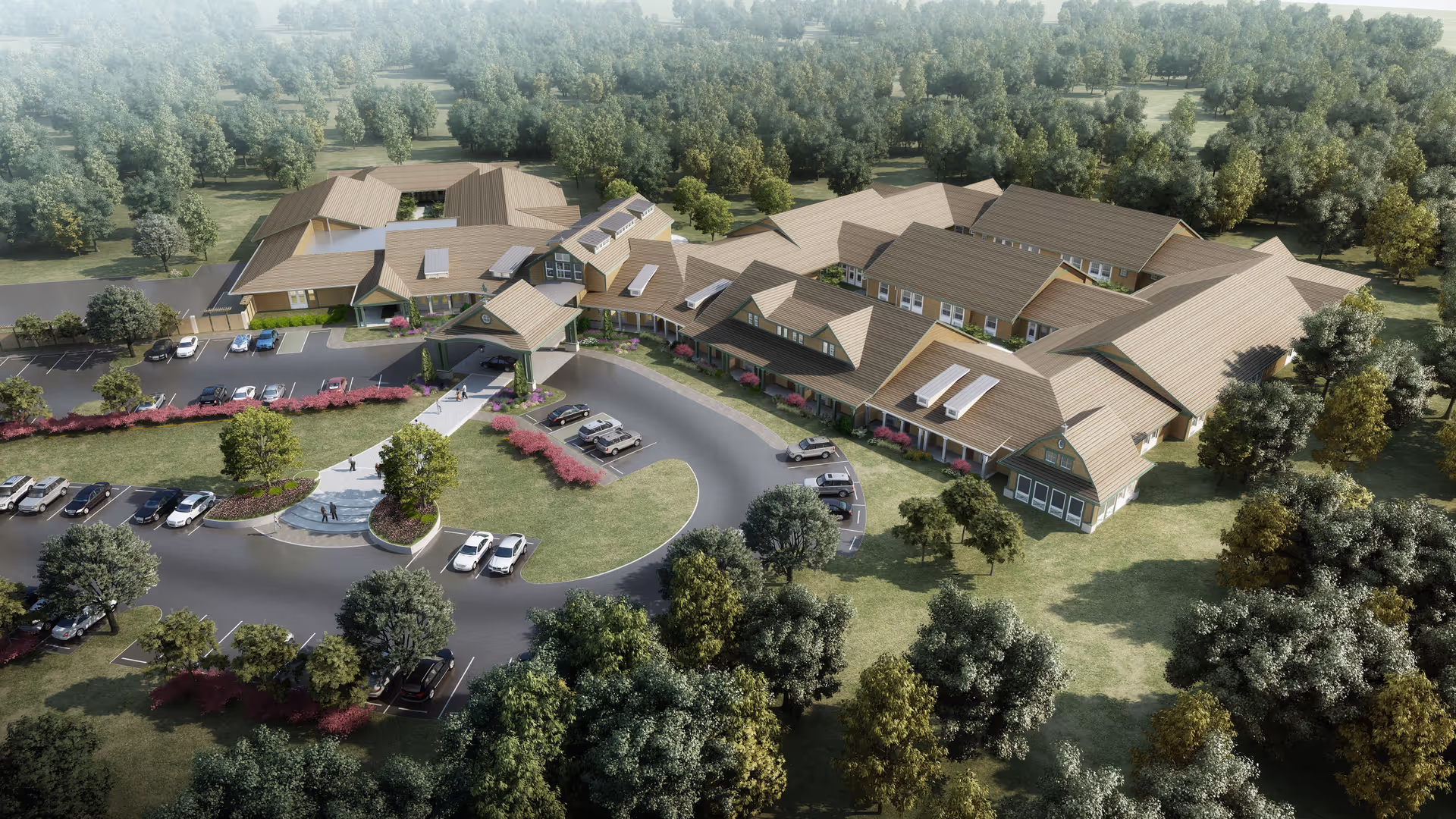 Aerial view of Thrive at Augusta senior living facility surrounded by trees and greenery, showing multiple connected buildings with tan roofs, a circular driveway with parked cars, and landscaped areas with bushes and trees.