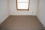 Small empty room with beige carpet, white walls, and a window with blinds.