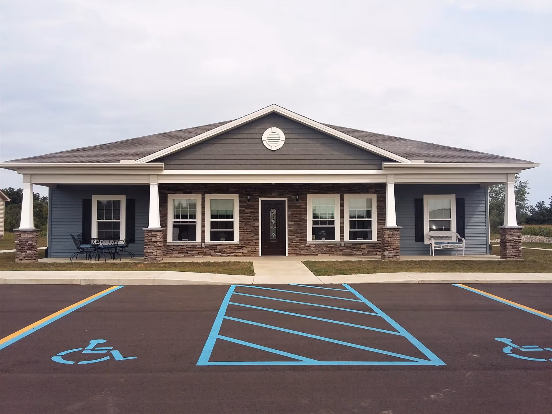 Front view of a single-story senior living facility with accessible parking in foreground.