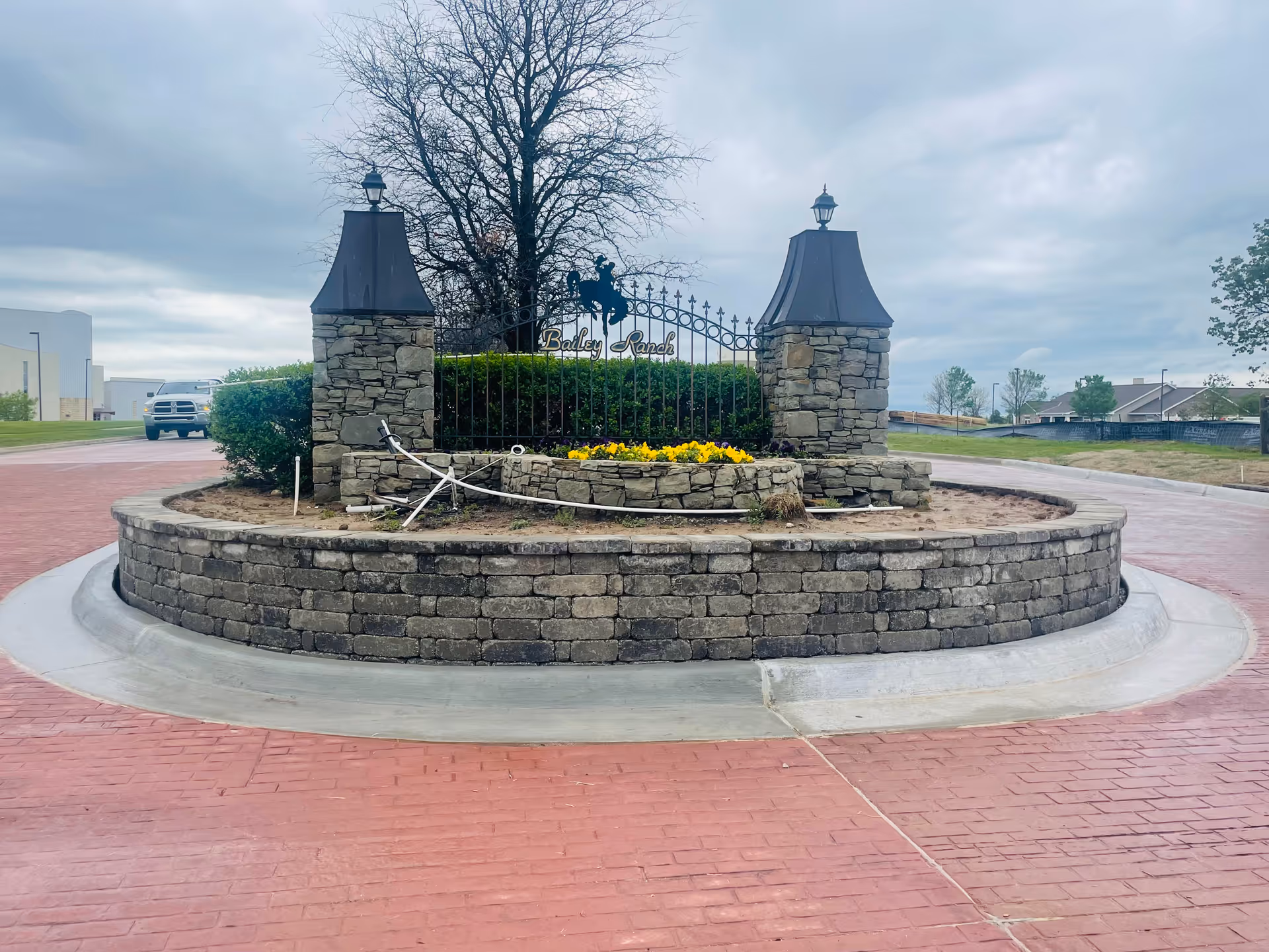 Circular stone planter with iron gate in a roundabout at a senior living facility.