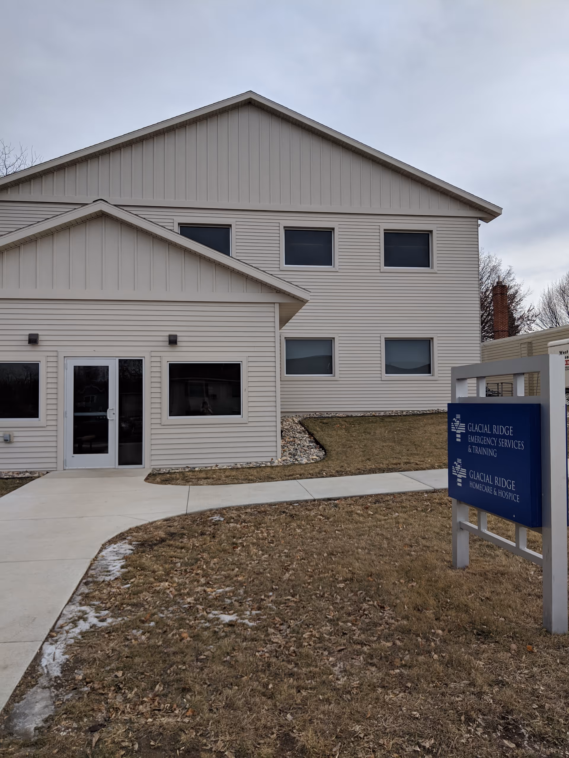 Two-story beige building with a Glacial Ridge Homecare & Hospice sign at the front.