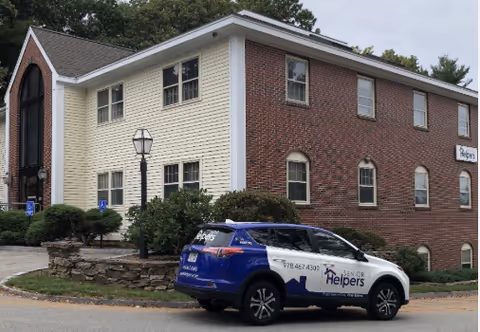Exterior view of a two-tone building with a Senior Helpers car parked out front