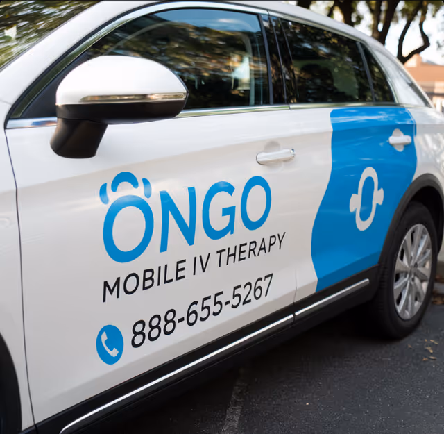 Side view of a white mobile IV therapy van with blue Ongo logo and contact number.