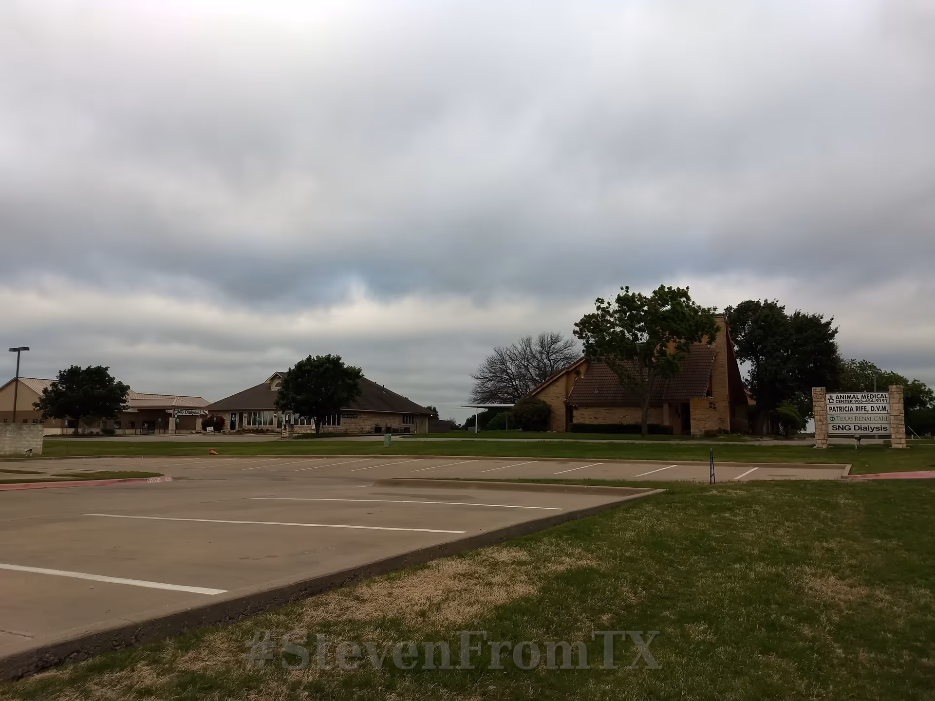 Exterior view of a senior care facility with parking and cloudy sky.