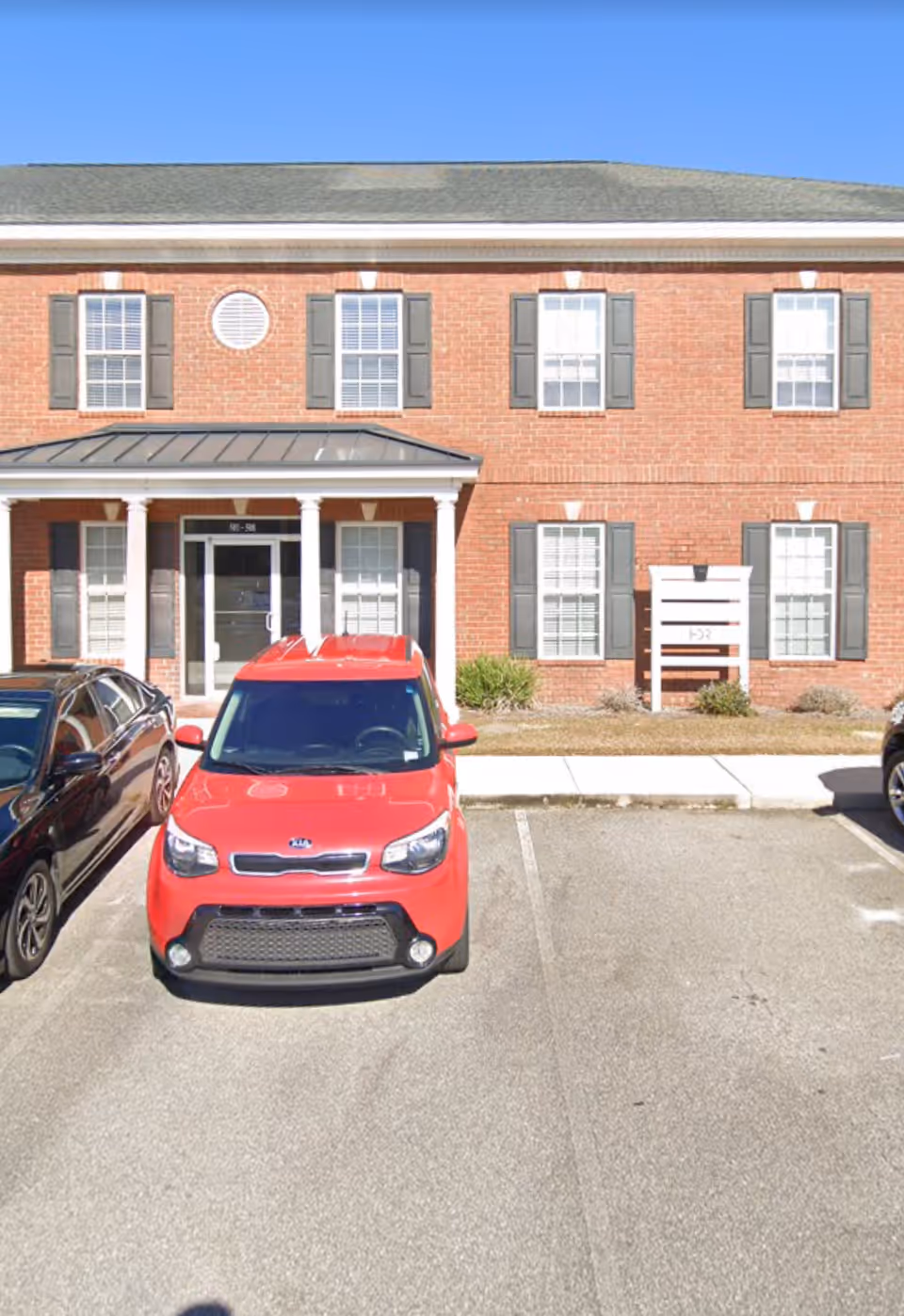 Brick senior care facility exterior with cars parked in front.