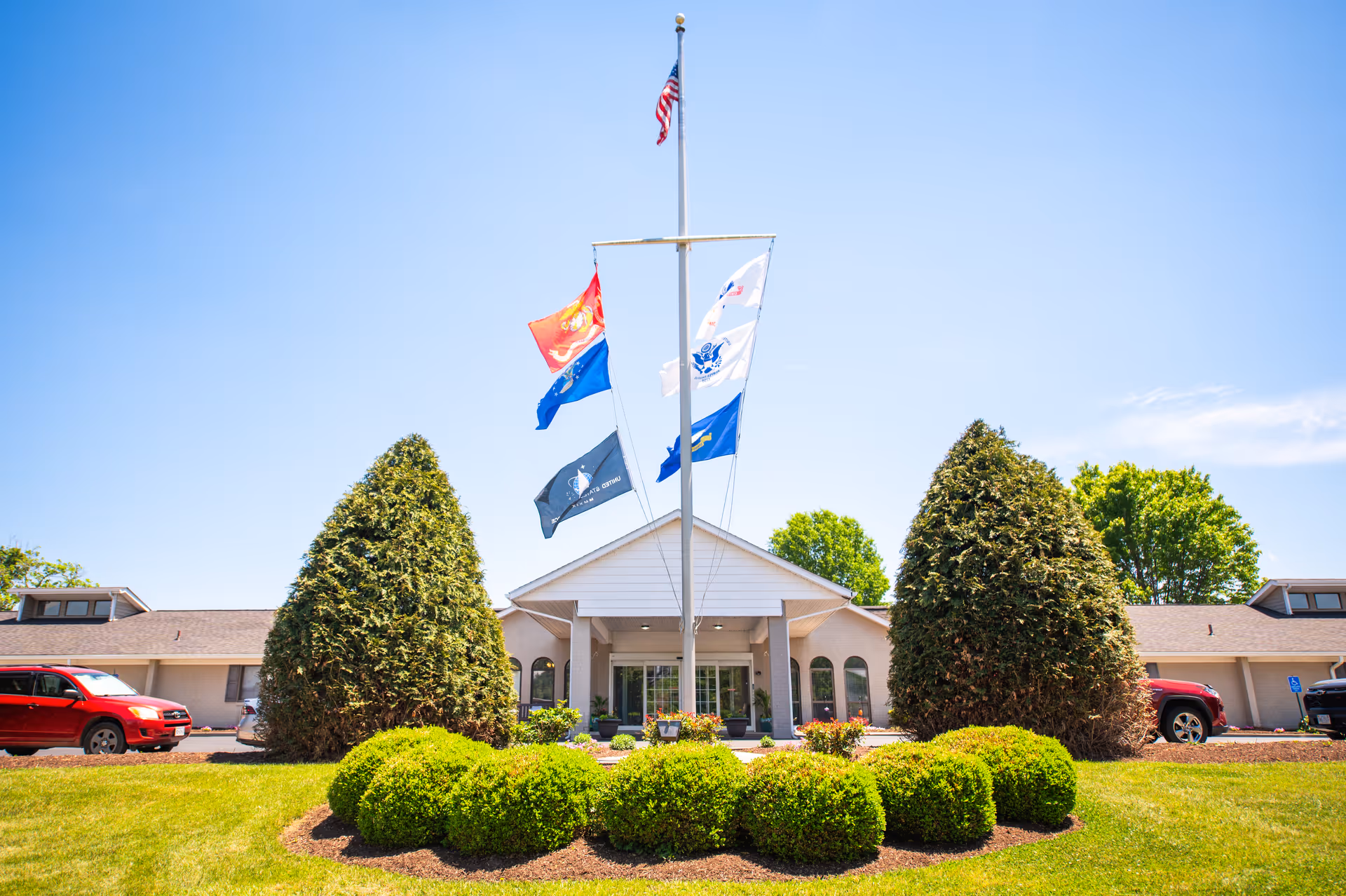 Front of Commonwealth Senior Living at Radford with flags and landscaped entrance