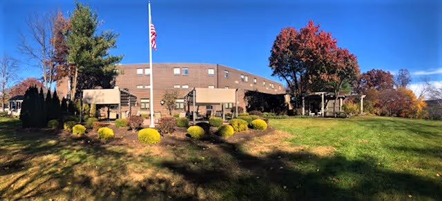 Exterior view of The Summit at Plantsville showing the building, flagpole, and landscaped lawn.