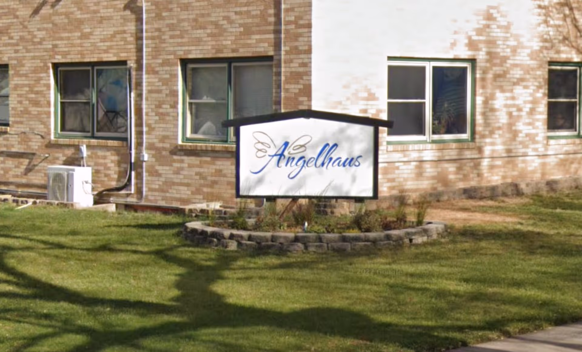 Brick building exterior with Angelhaus sign in a landscaped front yard.