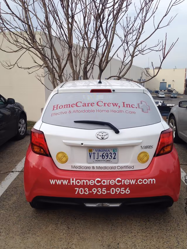 Rear view of a pink and white HomeCare Crew van in a parking lot.