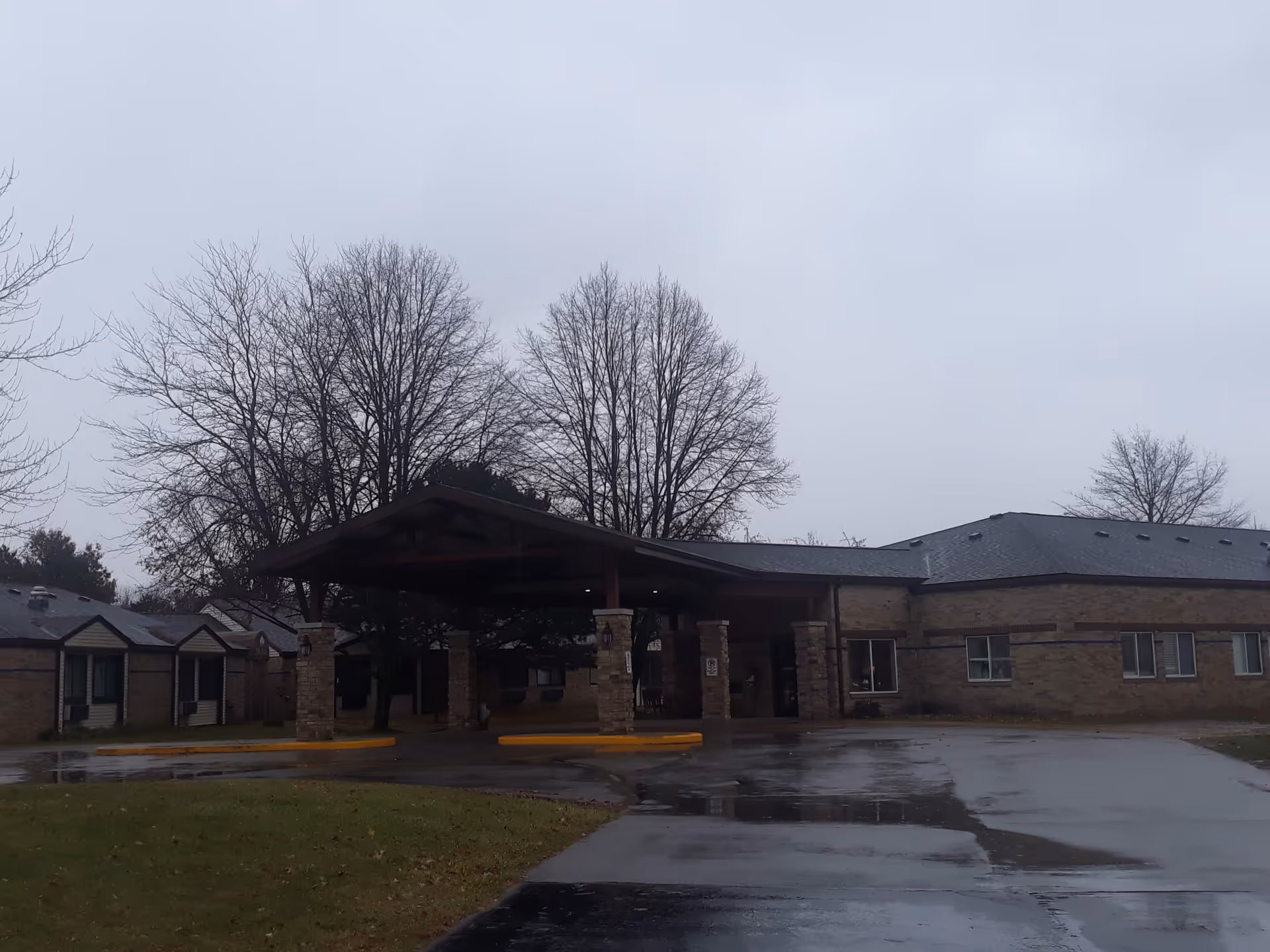 Exterior view of Thurston Woods Village showing a covered entrance and leafless trees.