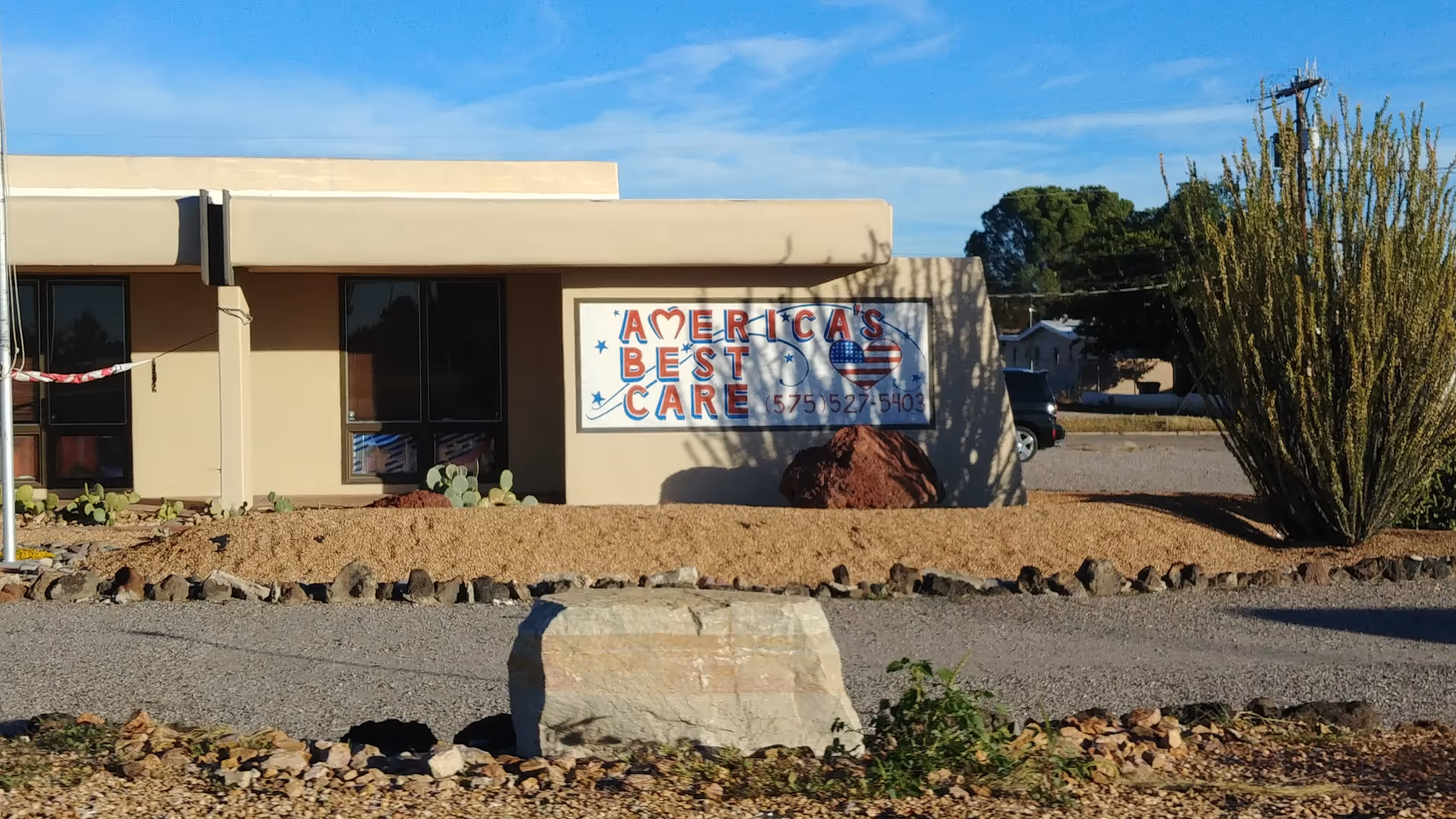Exterior view of America's Best Care facility with a sign and desert landscaping.