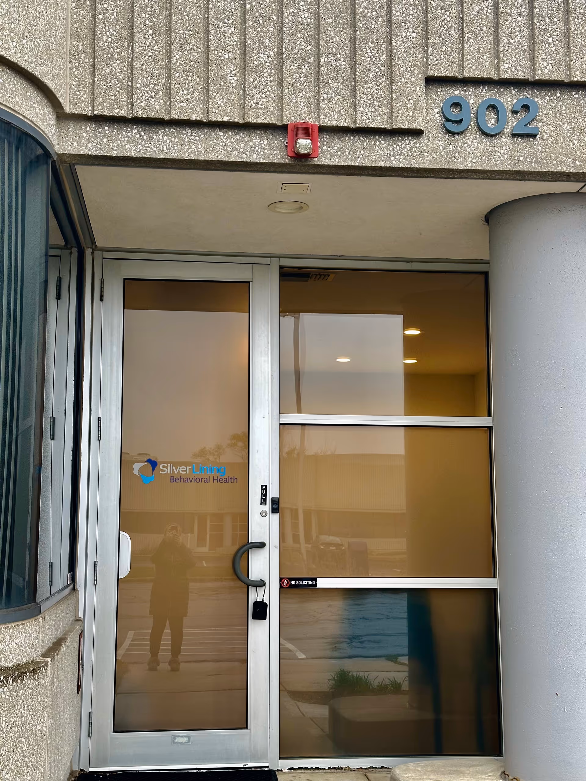 Glass entrance door displaying Silver Lining Behavioral Health logo, with building number 902.