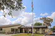 Exterior view of a single-story care center with flagpole and green lawn.