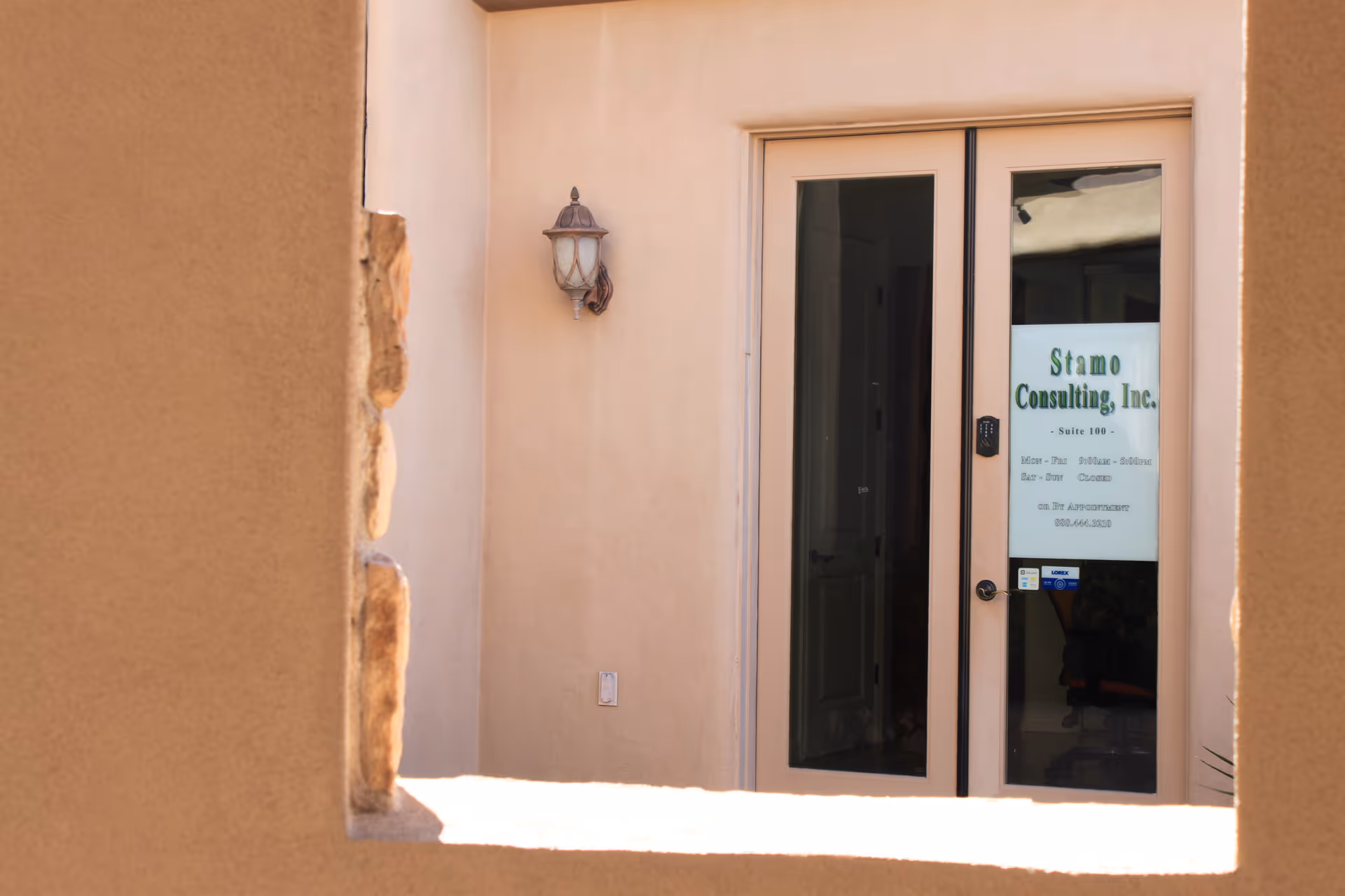 Exterior doorway of a beige building with a glass door labeled Stamo Consulting, Inc.