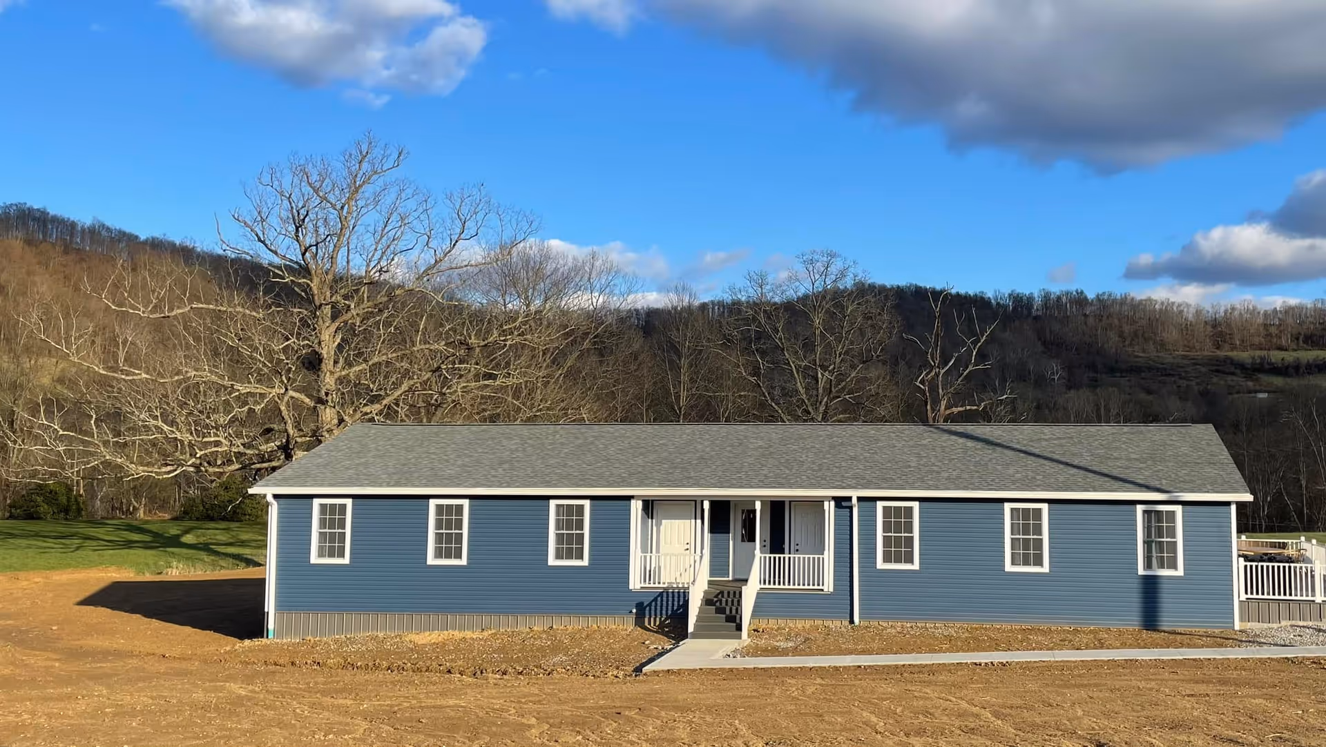 Blue single-story senior care facility exterior with white trim and natural landscape.