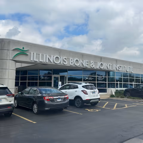 Front view of Illinois Bone and Joint Institute building with parked cars in a lot.